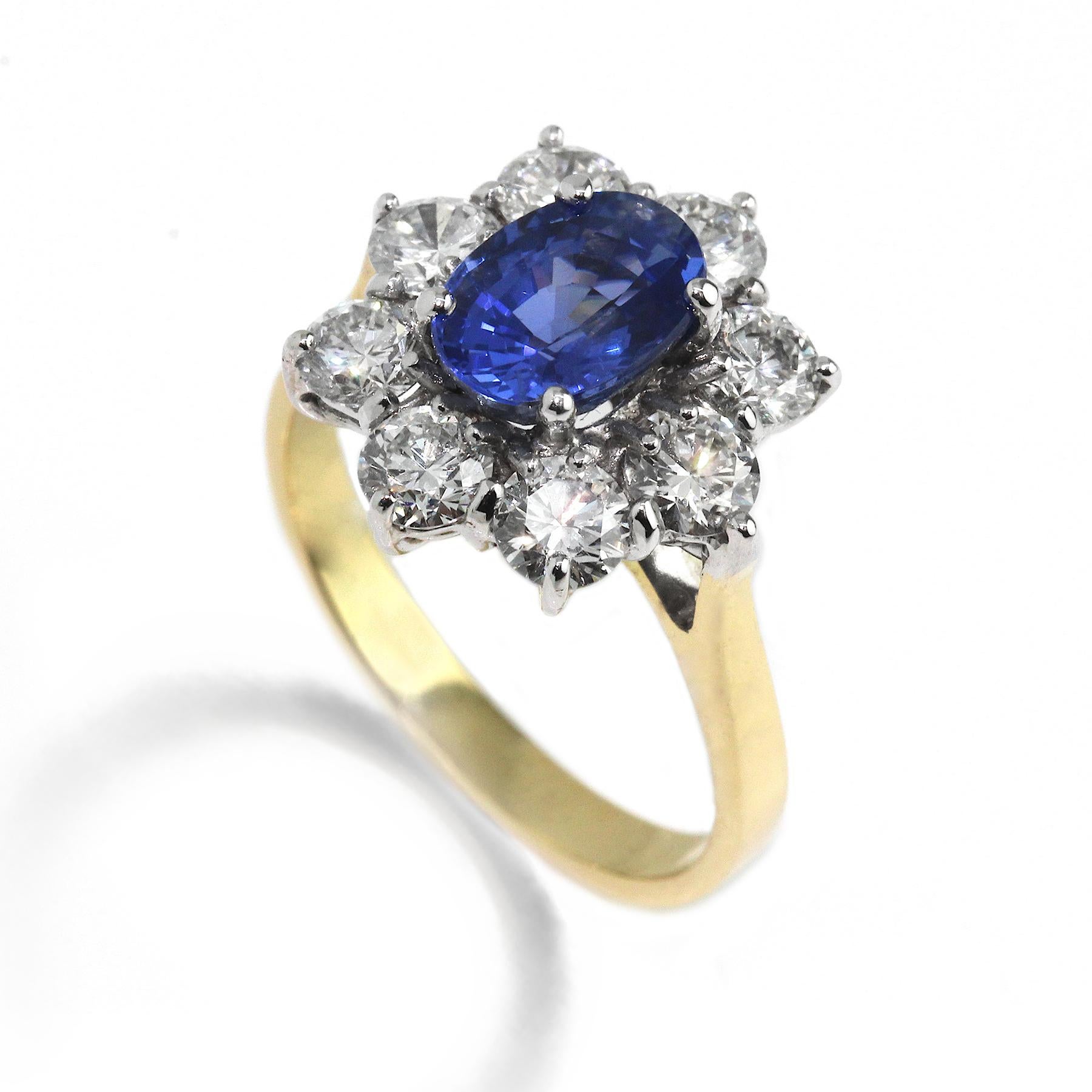 An elegant cluster holding an exquisite sapphire in 18k yellow and white gold. A variation of the classic cluster made with 8 diamonds (1.67ct F VS) surrounding a fine blue sapphire (2.03ct). 
Ring Size: M 1/2. Band Width: 2.7mm. Setting diameter:
