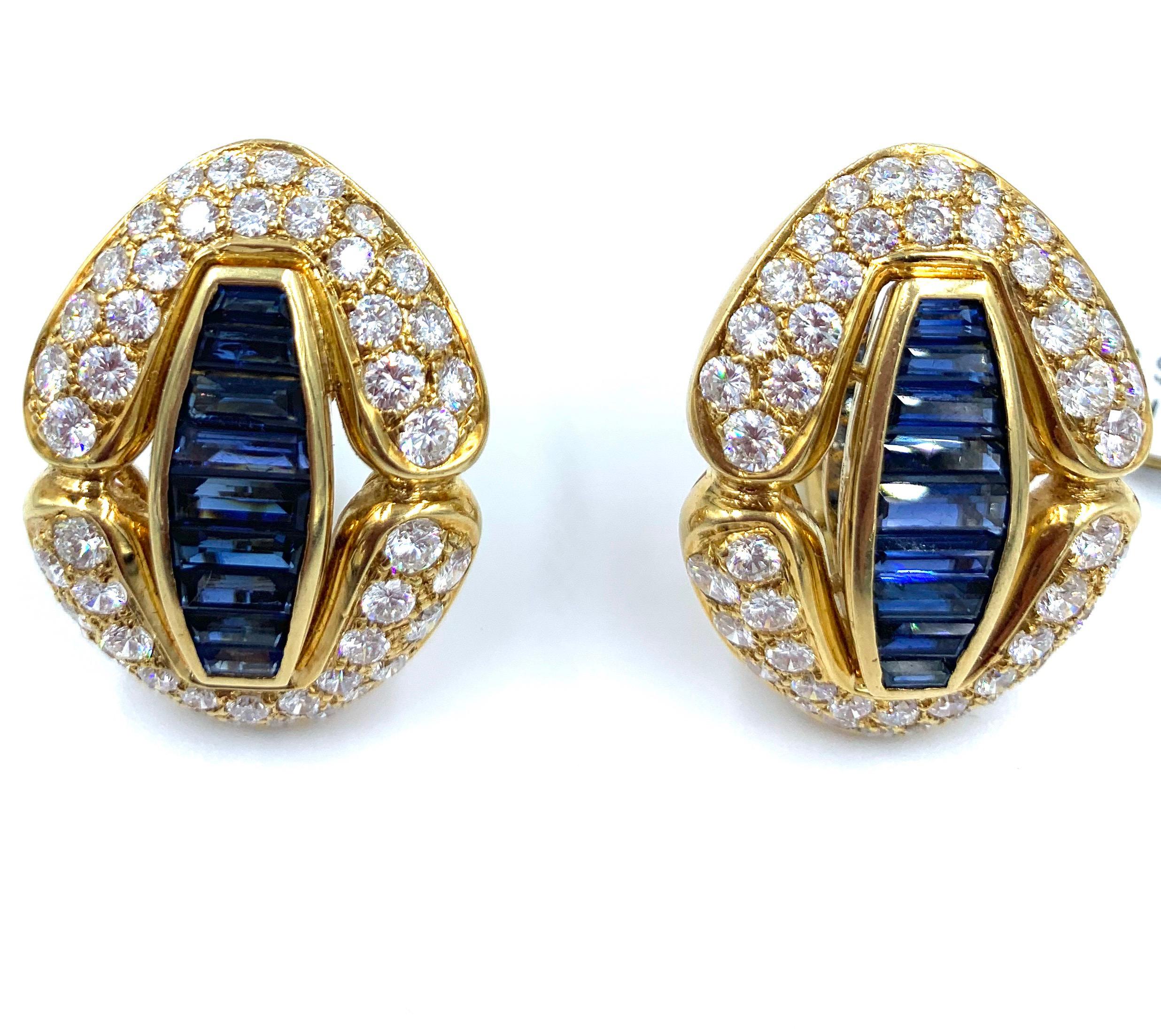 Uniquely designed, these lovely solid 18k yellow gold earrings are adorned with sapphires and diamonds. In the center, a row of beautifully cut sapphire baguettes,  totaling 6 carats. Surrounding the sapphires, are two shapes that create the effect