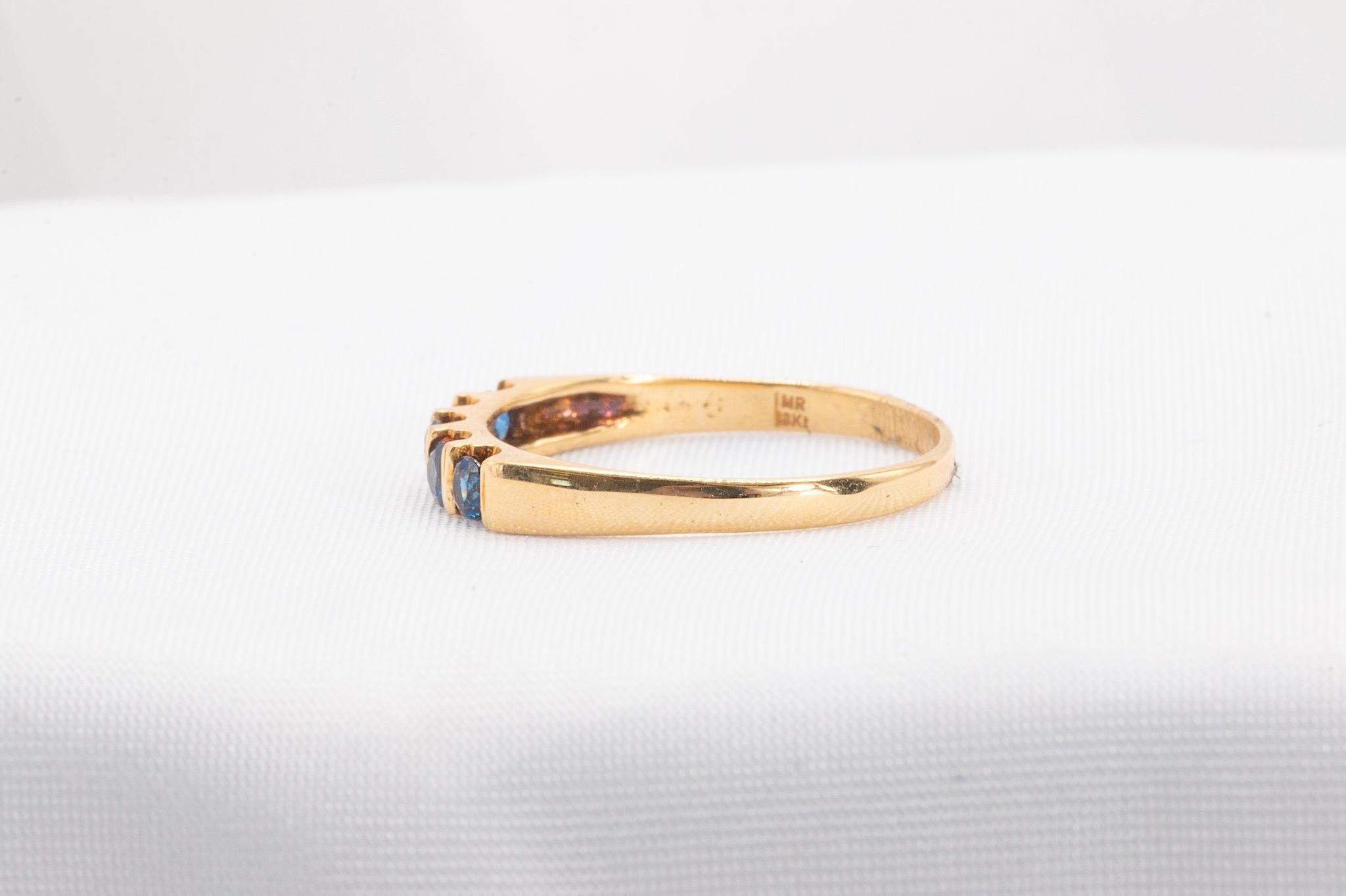 This stunning pre-owned sapphire band is a timeless addition to any collection. Crafted in 18K yellow gold, the ring features 5 round sapphires set elegantly in a sleek design. Weighing 1.6 grams, it is both lightweight and luxurious. Currently a