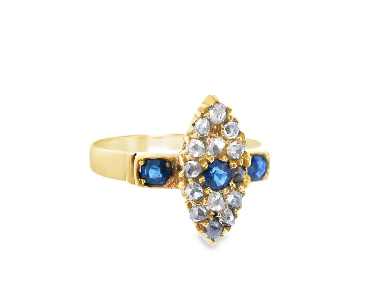 Cette magnifique bague en or jaune 18 carats est ornée d'un saphir et d'un diamant de taille ronde. Le centre de la bague est de forme ovale avec des extrémités pointues, et présente un saphir rond central entouré d'une grappe de diamants taillés en