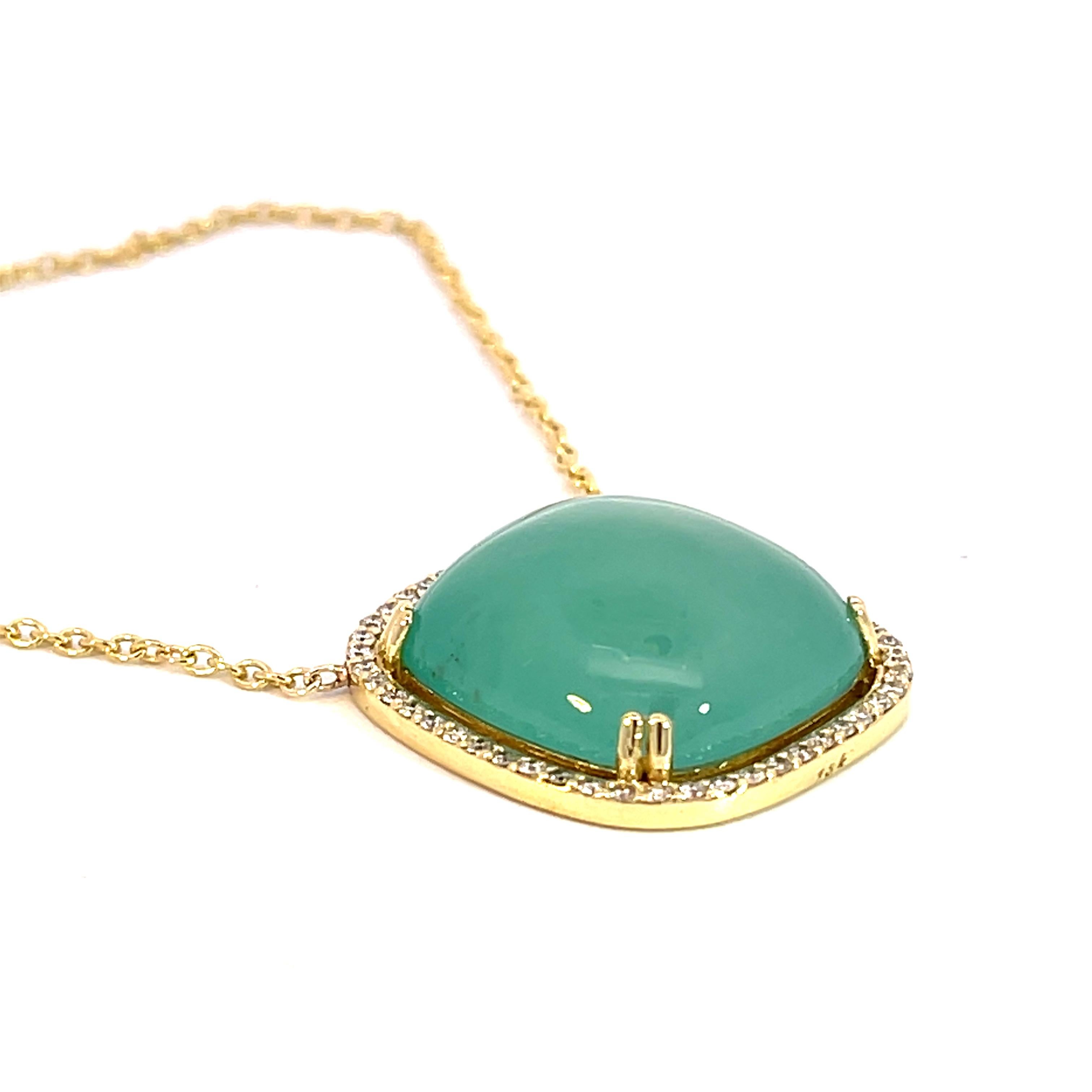 An 18k yellow gold pendant featuring a double prong set African cushion cut cabochon sea foam chalcedony (16.60 carats) which is accented by a halo of white diamonds 0.30 total carat weight on a 1.5mm 14k yellow gold cable chain. This necklace was