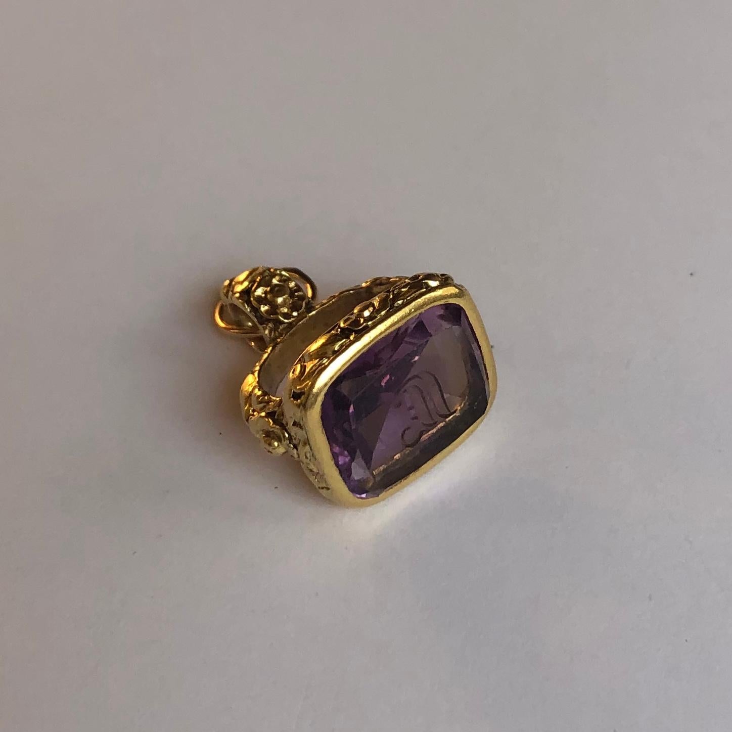 18k yellow gold seal with amethyst. 
The gold element symbolically represents a crown, symbol of success and power while the amethyst is hand carved with the initials ( IF).
The Amethyst, transparent and of deep violet colour is a rectangular cut