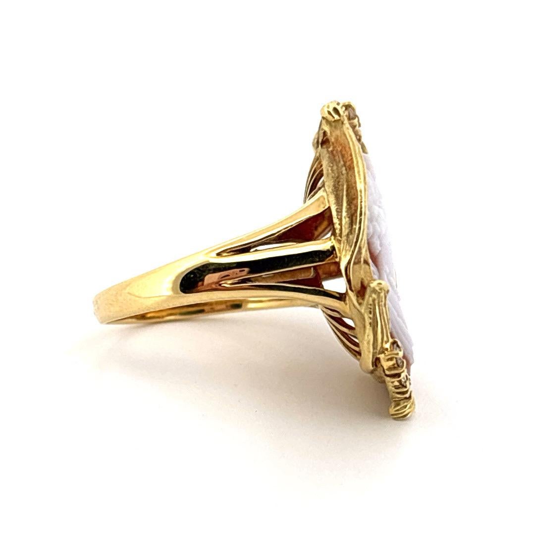 Dieser exquisite Ring aus 18 Karat Gelbgold zeigt eine fein geschnitzte Muschelkamee, die ein klassisches weibliches Profil mit bemerkenswerter Detailtreue und Eleganz abbildet. Die Kamee wird zart umrahmt von einer fließenden, von Blättern