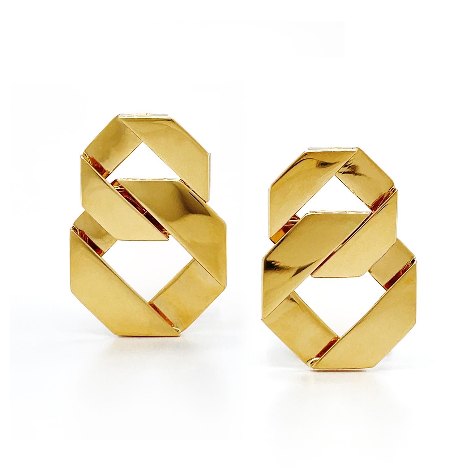 The sophisticated incorporation of geometric shapes creates a modern design. An enclosed 18k yellow-gold ribbon is folded to form an octagon. Interlocked is a larger ribbon of octagon, which descends below. The metal is given a satin finish for a