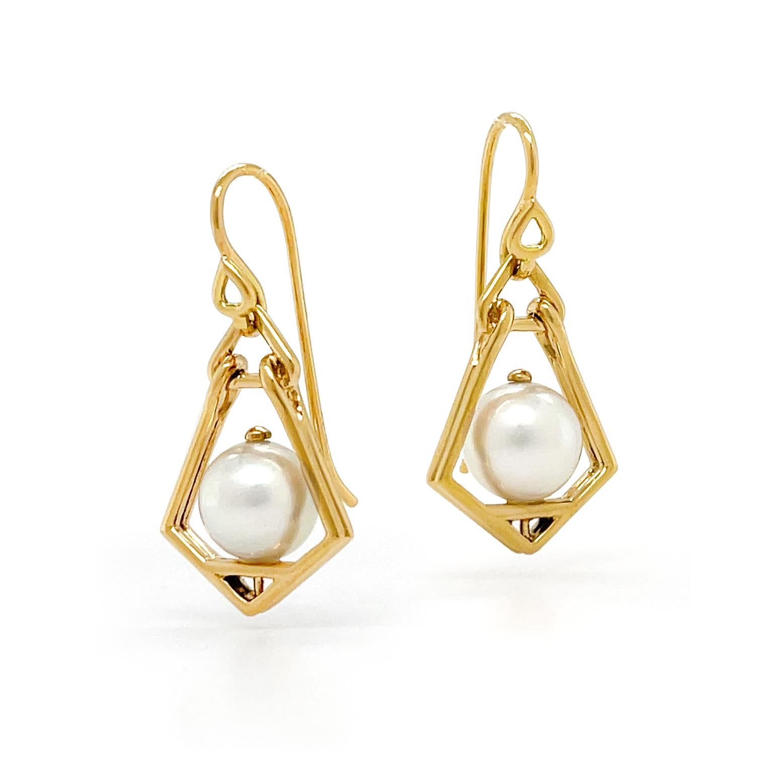 Warmth joins elegance in these drop earrings. 18k yellow gold bars form the shape of an antique lantern. An Akoya pearl in the center represents a fiery glow and French hooks complete the design. The earrings measure 0.57 inches (width) by 1.2