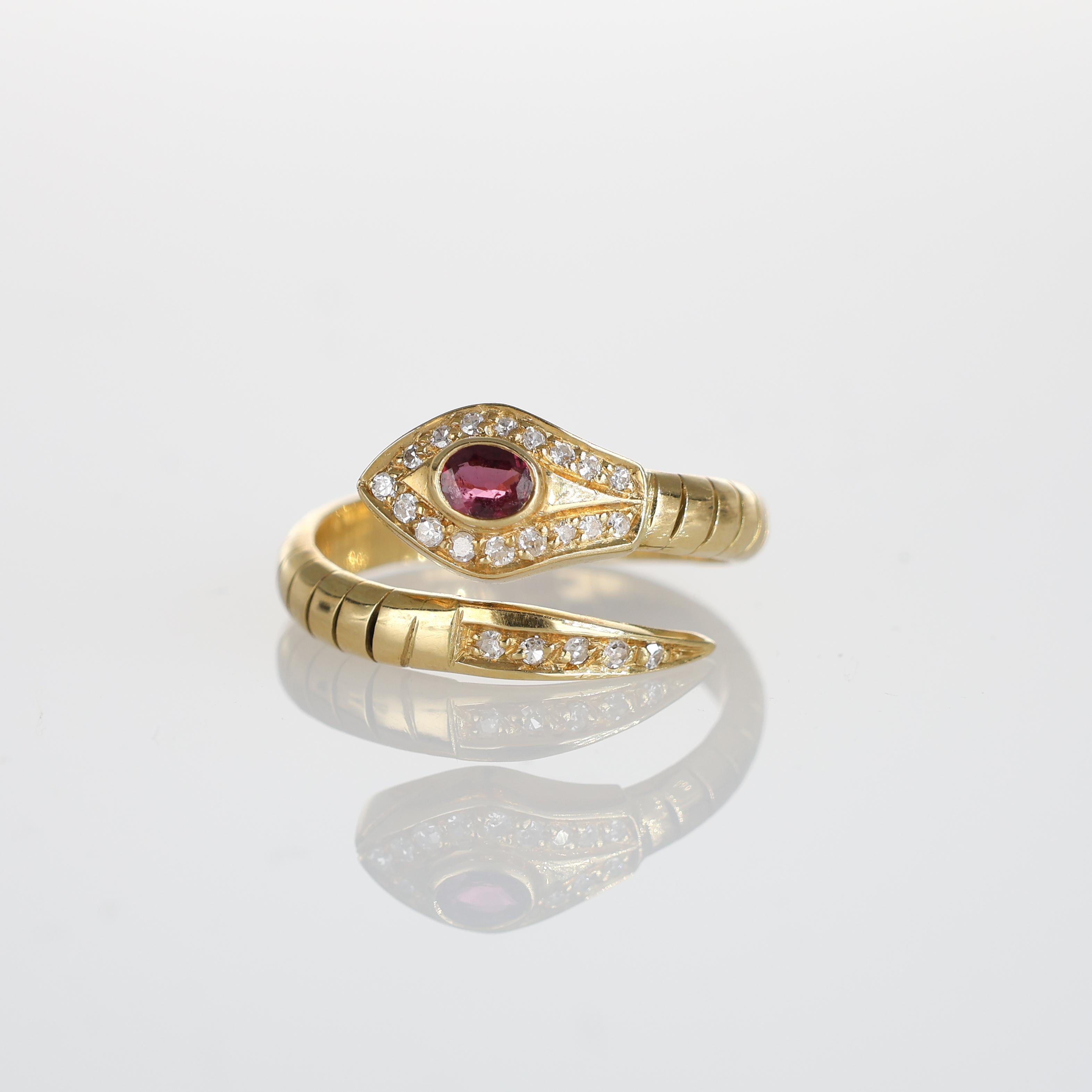 A unique and elegant snake-inspired ring crafted in 18k yellow gold. Featuring a captivating oval ruby at the center, the design is accented by a shimmering pavé of brilliant-cut diamonds, adding a luxurious sparkle. This distinctive piece merges
