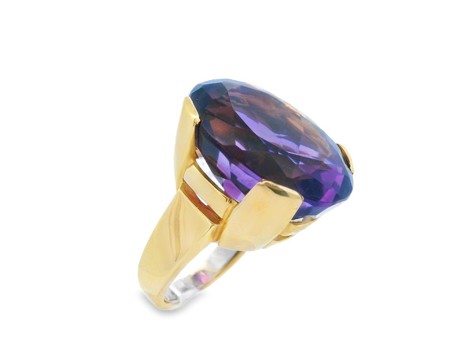 Cette magnifique bague est composée d'or jaune 18k et d'une grande améthyste de taille ovale. L'améthyste pèse au total 32,4 grammes en carats et arbore une riche teinte pourpre soyeuse qu'il est difficile de ne pas remarquer. La forme ovale permet