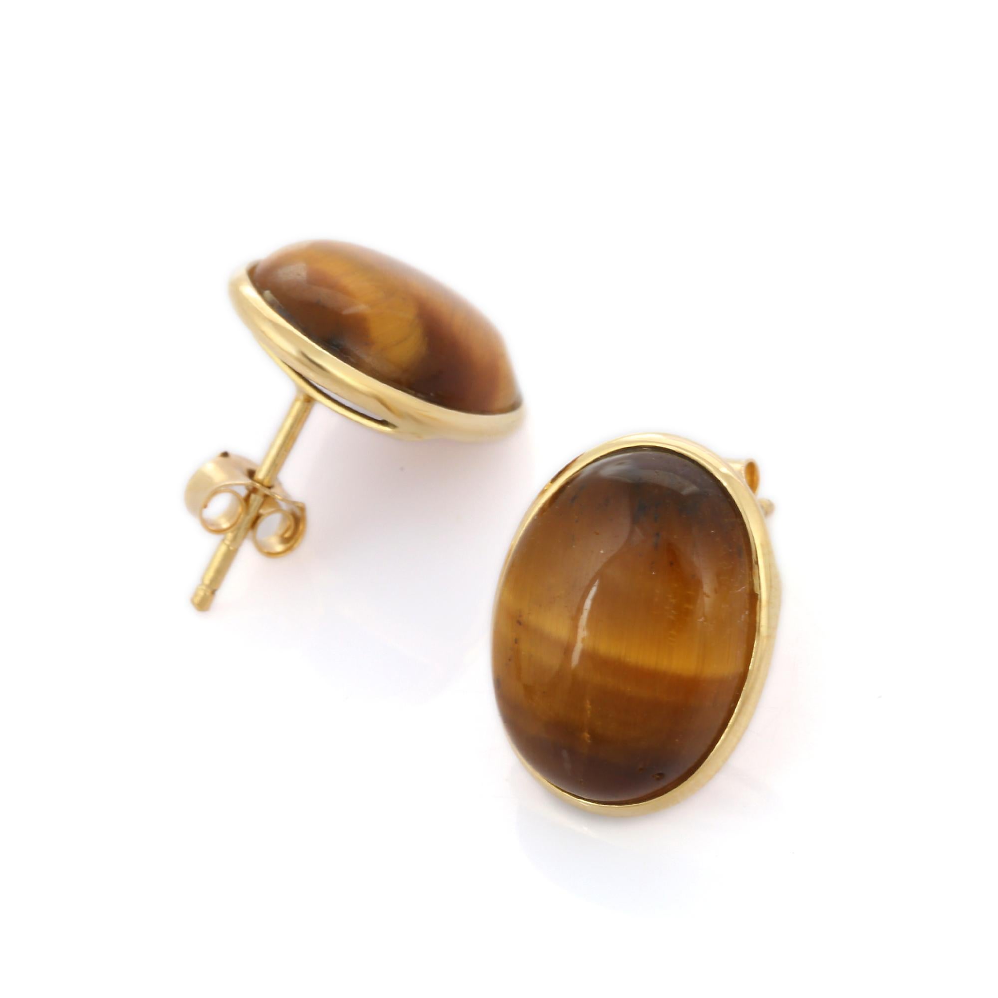 Studs create a subtle beauty while showcasing the colors of the natural precious gemstones making a statement. 
Cabochon oval cut tiger's eye stud earrings in 18K gold. Embrace your look with these stunning pair of earrings suitable for any occasion