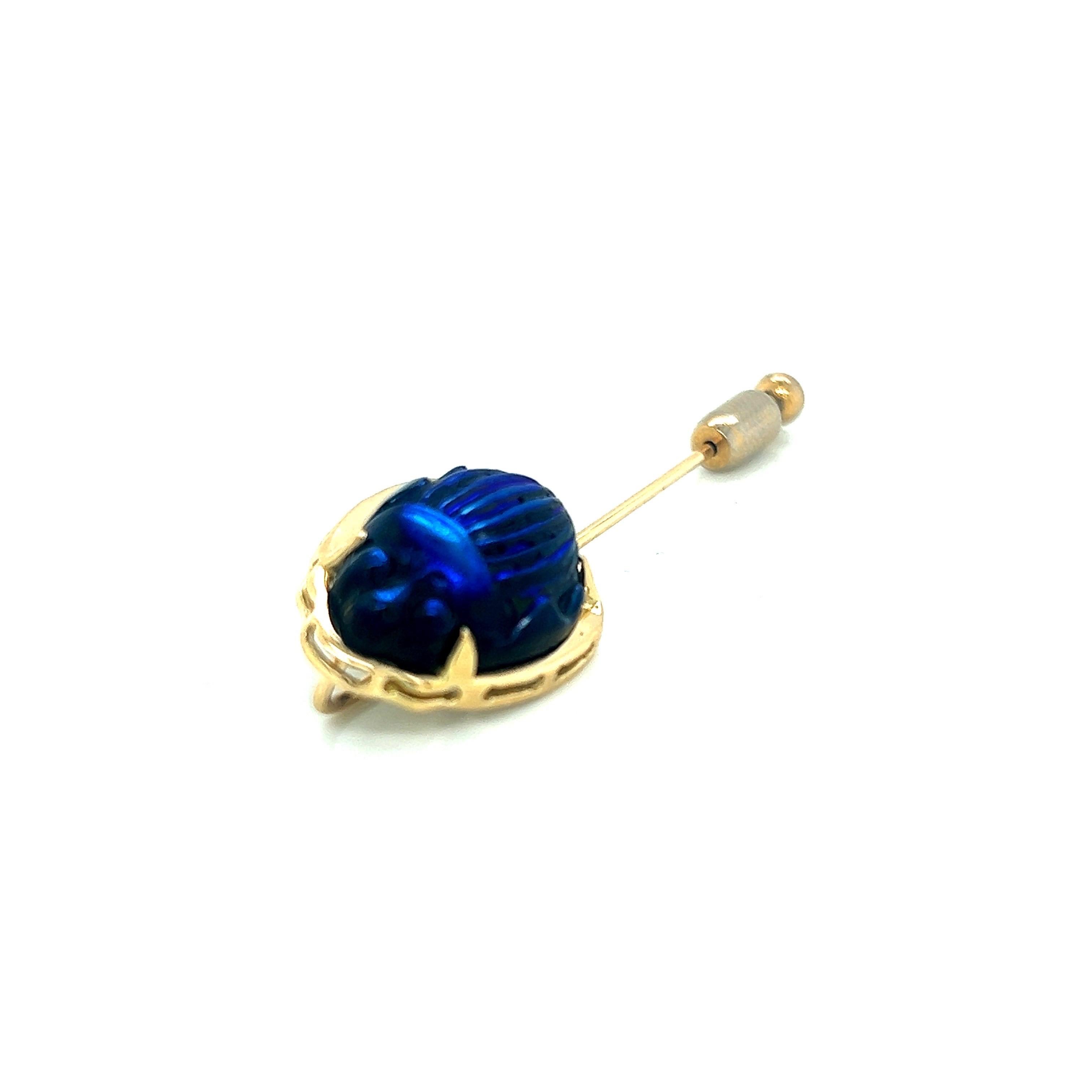 This stick/lapel pin is a breathtaking piece of jewelry that beautifully combines luxurious 18k yellow gold with shimmering Favrile cobalt blue glass scarab. Crafted by skilled artisans, this pin exudes sophistication and timeless elegance.

The