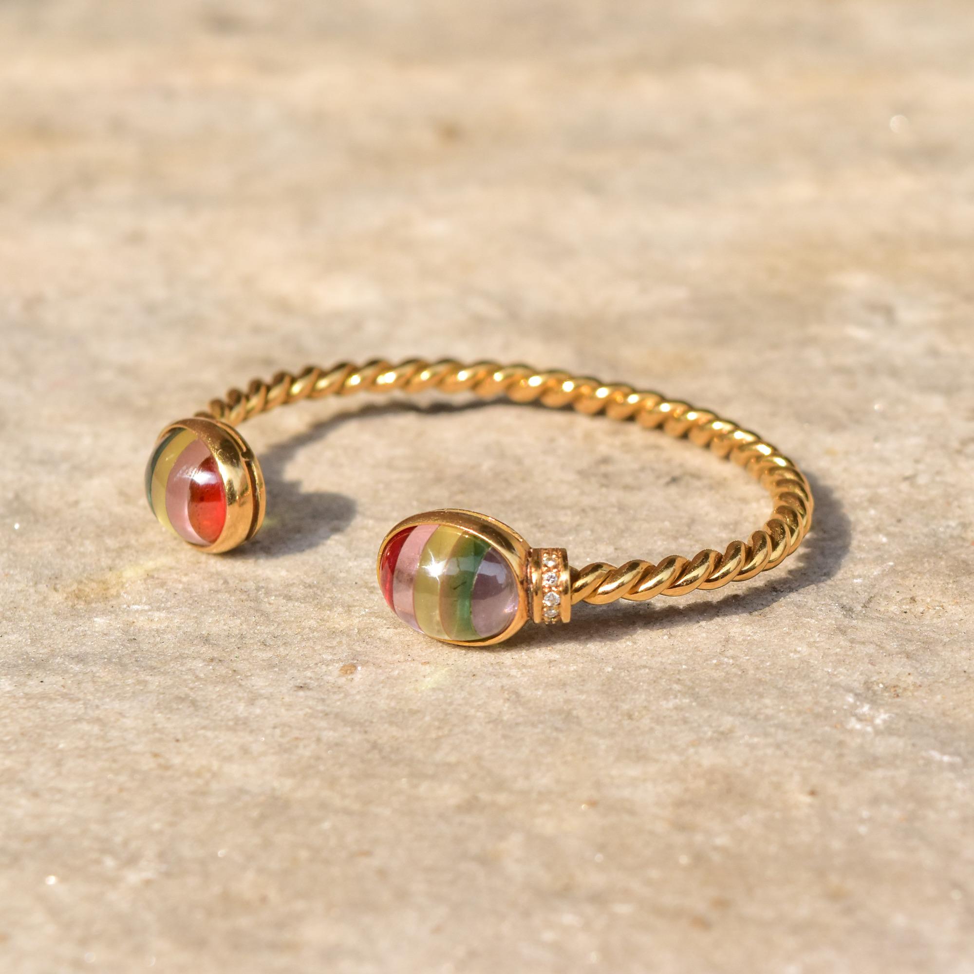 An incredibly unique 18K yellow gold striped glass cabochon cuff bracelet with diamond accents. Features a solid gold spiral rope chain bracelet, 4mm in diameter, with a multi-color glass cabochon bezel set on each end with a 5-diamond pave design