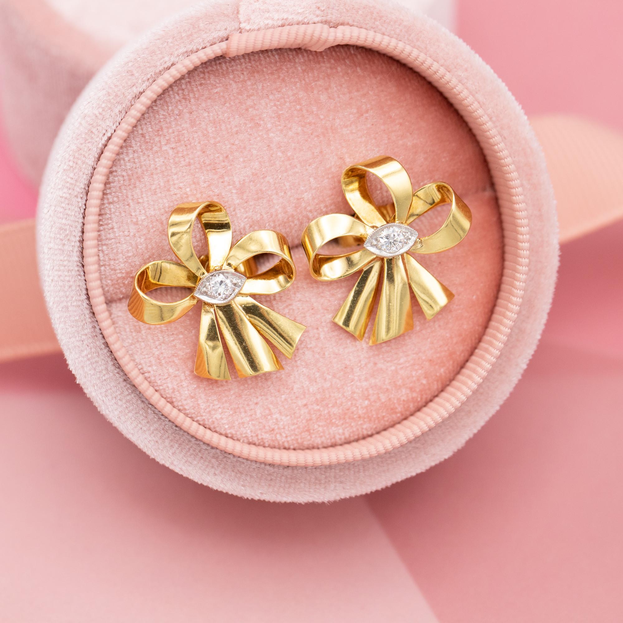 For sale is this 18 K yellow gold pair of diamond earrings. This beautiful pair is set with two brilliant cut diamonds which combine for approximately 0,2ct. They are set in a marquise shaped white setting inside an elegant bow shape. They date back