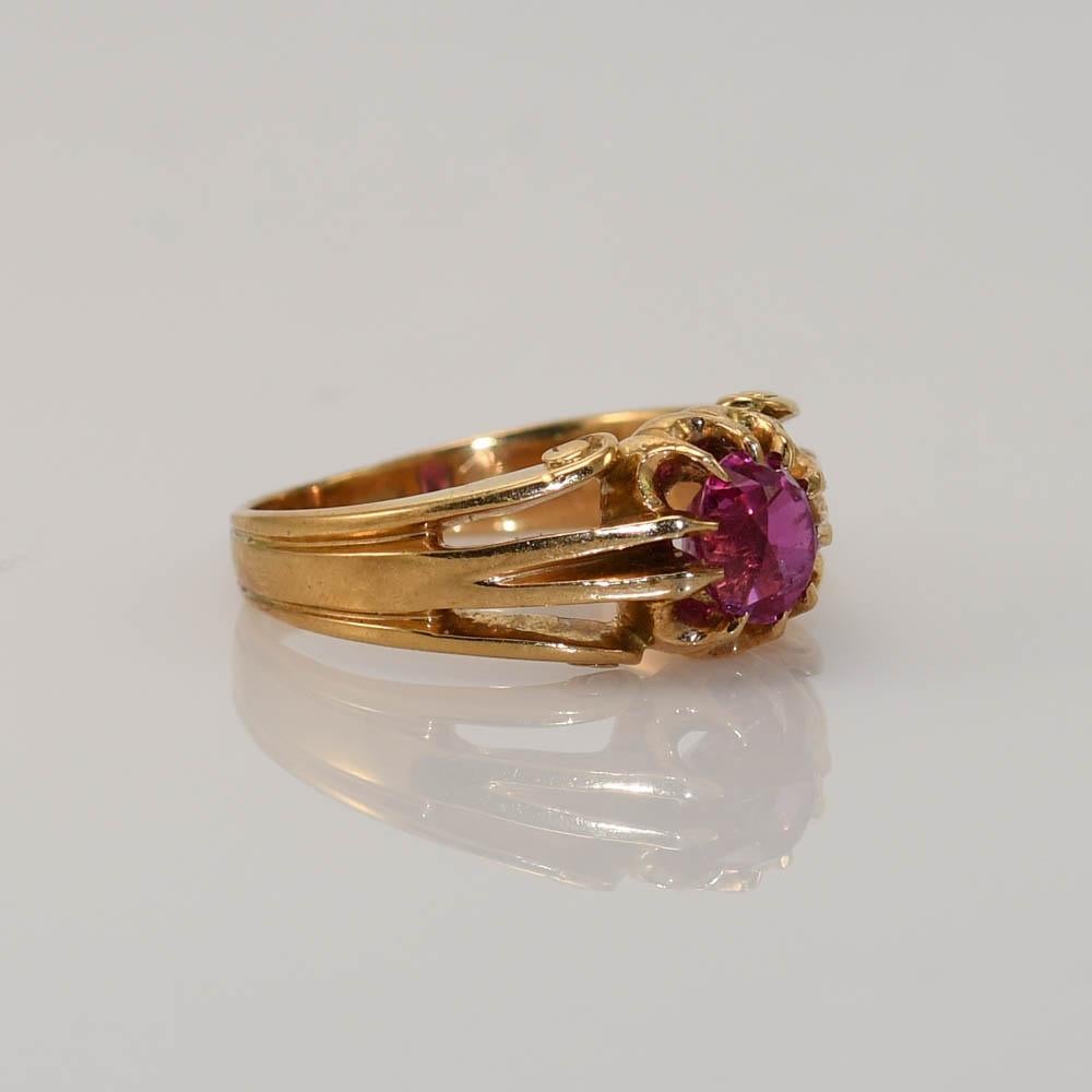 One 18K yellow gold Vintage ring with a oval synthetic pink sapphire.
This ring has a scroll design on the sides and has 10 claw prongs holding in the stone.
6mm x 5.5mm.
It appears to be oval in the setting.
The stone does have a really high