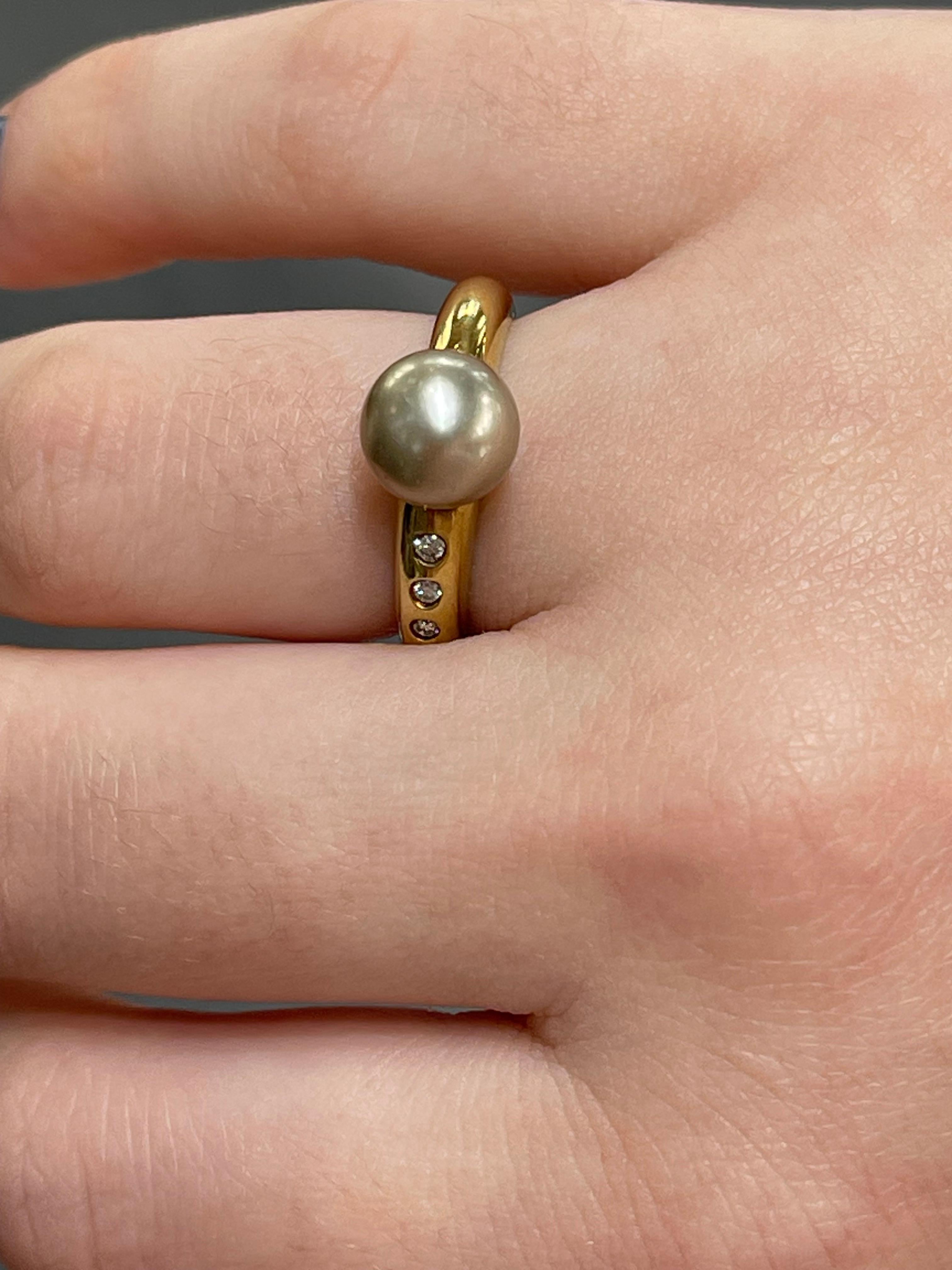 Bague en or jaune 18k avec perle de Tahiti et diamant .06 CTW. Cette bague comporte trois diamants ronds sur le côté de la perle, le diamètre de la perle est de 8 mm, la taille de la bague est de 6 1/4, et son poids total est de 6,65 grammes.