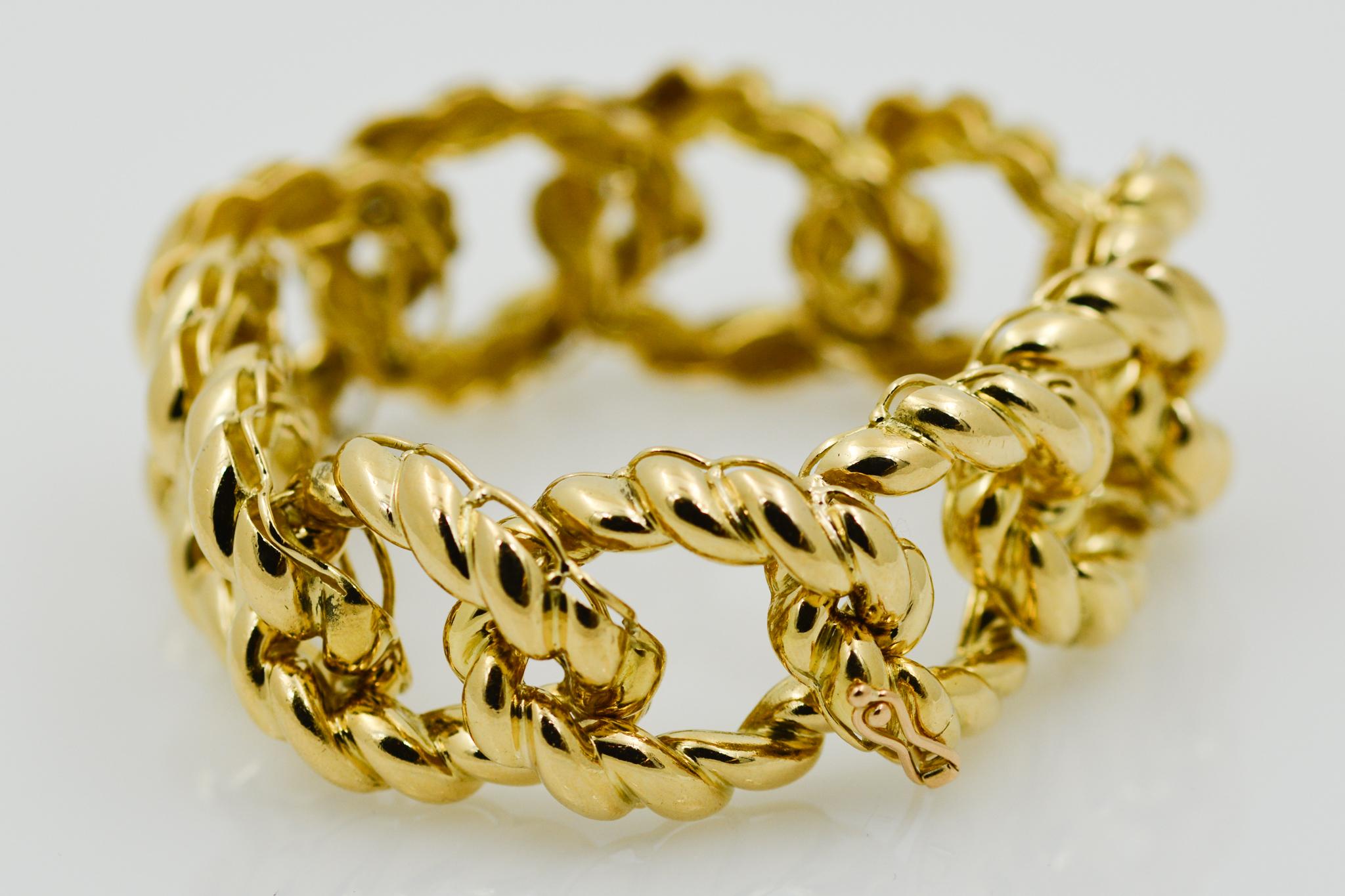 This 18 karat yellow gold curb link bracelet has a rope texture finish and measures at 24.50mm wide and 8 inches long with a hidden clasp. 