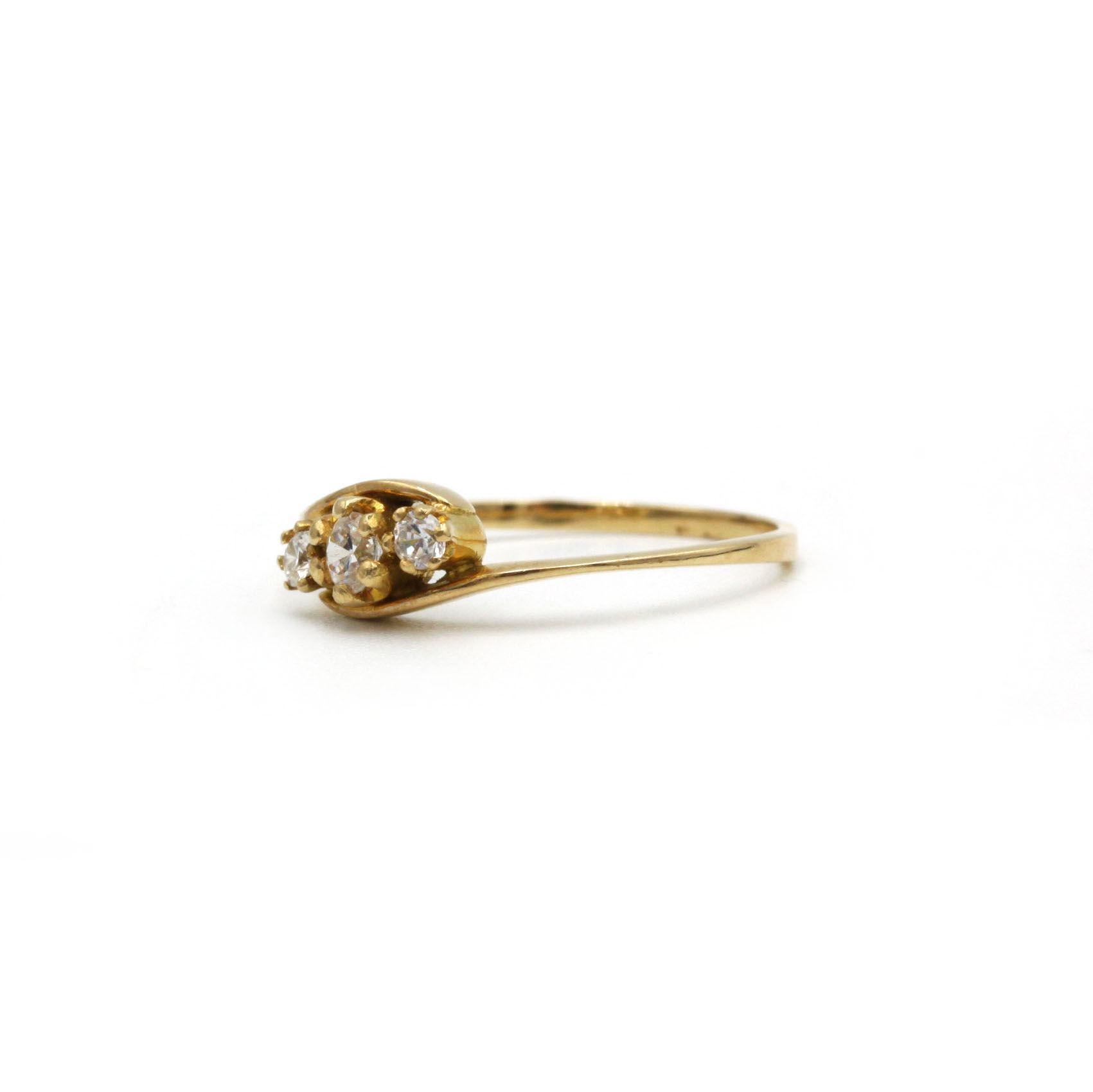 Questo anello in oro giallo 18 carati, che strizza l'occhio al design dell'inizio del XX secolo, presenta un trio di diamanti tondi brillanti (circa 0,28 carati in totale) incastonati in un grazioso motivo a spirale. La fascia sottile e lucida