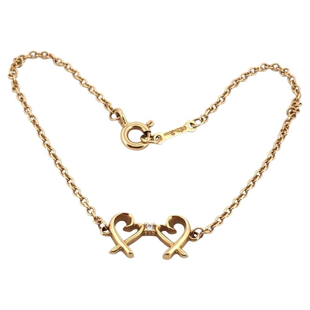 Fabriqué par Tiffany & Co, cet élégant bracelet de la collection Paloma Picasso est orné du motif emblématique du double cœur d'amour, symbole d'affection et de connexion intemporelle. Conçu en luxueux or jaune 18 carats, le bracelet présente deux