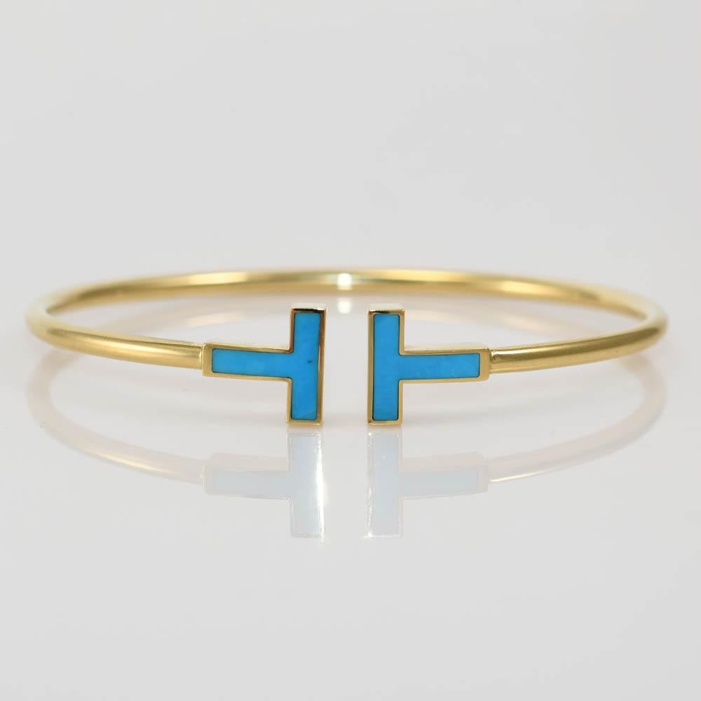 Tiffany & Co  T wire bangle bracelet with turquoise inlay.
Stamped T & Co. AU 750 and weighs 6.8 grams.
The bracelet has an internal measurement of 6 inches and expands a little.
The thickness is 2.5mm. Excellent condition.
Comes with original
