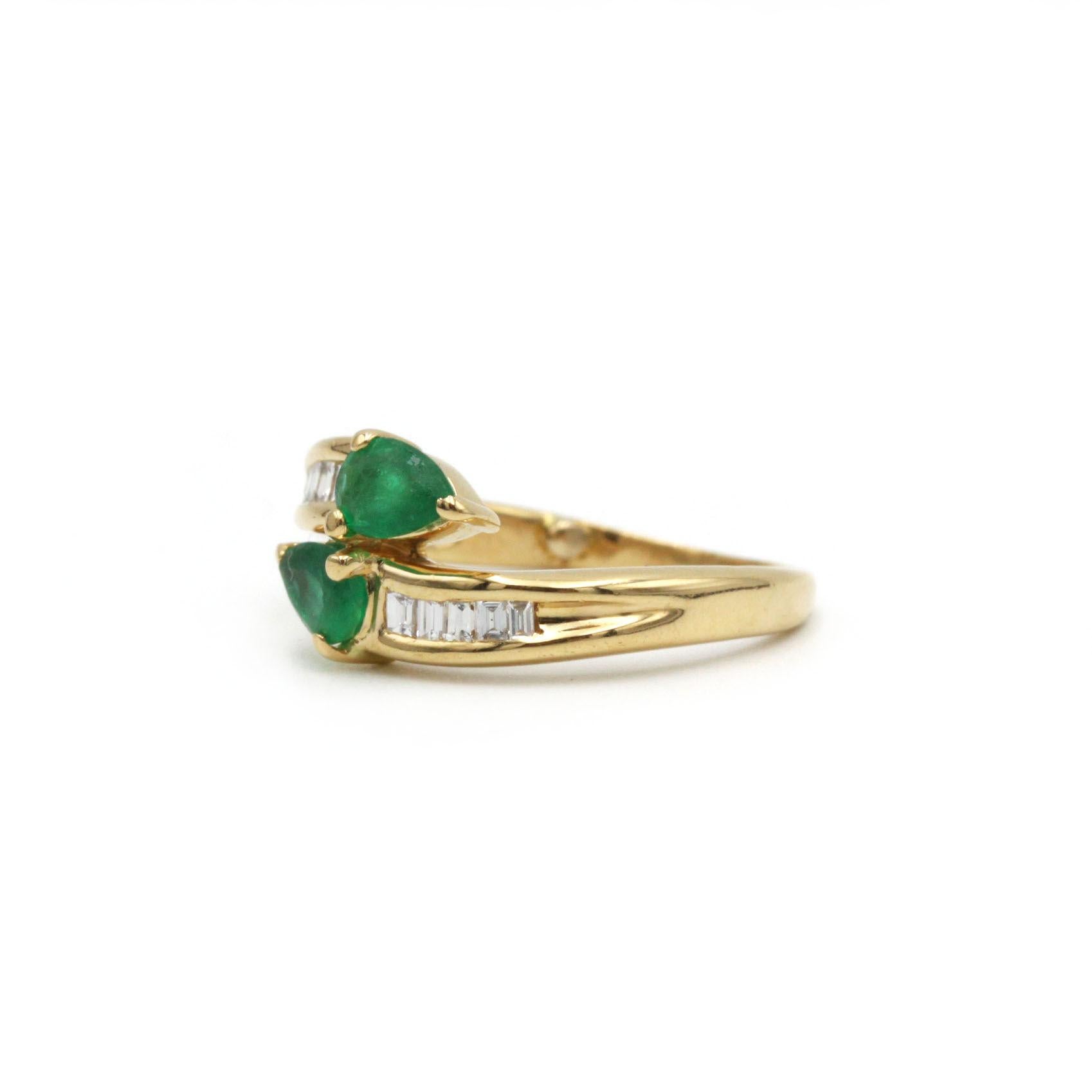 Cette élégante bague Toi et Moi réunit deux vibrantes émeraudes en forme de poire - chacune totalisant environ 1,00 carat - serties en position opposée pour symboliser l'union et l'harmonie. Les émeraudes sont flanquées de dix diamants baguettes