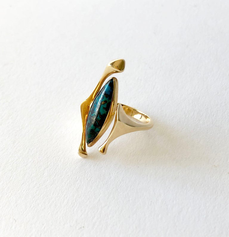 An 18K yellow gold ring featuring a 20mm by 6.5mm marquise shaped turquoise, possibly designed by Donald B. Wright of Oregon.  Ring is a finger size 6 to 6.5 due to its unusual, open design which does have a bit of give. It is signed 18K on the