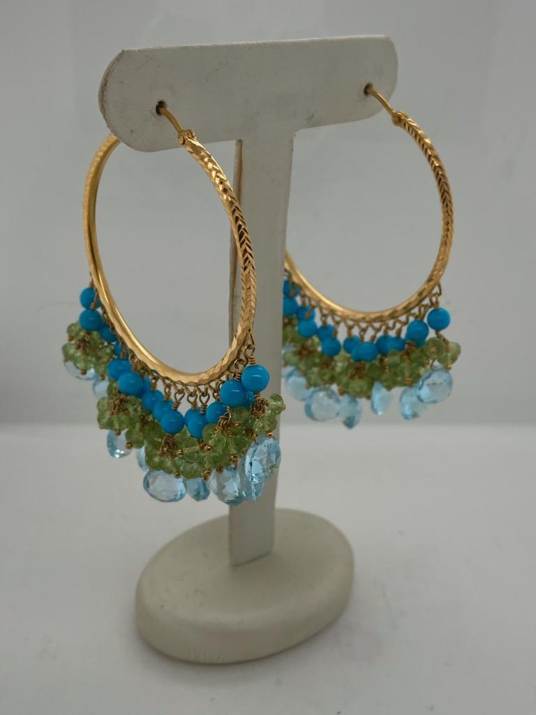 18K yellow gold custom large engraved hoop earrings. Dangling are 18 blue topaz briolettes, multiple faceted peridot beads and 32  3mm turquoise beads and weighing a substantial 37.8 grams. These stunning hoops really make a statement!
