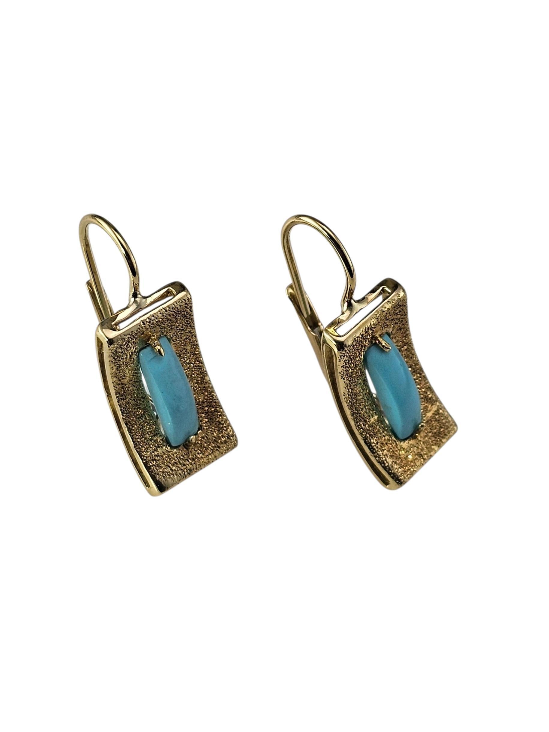 Boucles d'oreilles pendantes en or jaune 18K - Turquoise

Ces jolies boucles d'oreilles sont composées de turquoises lisses serties dans de l'or jaune 18 carats. Les montures dorées texturées ajoutent de la dimension et de la chaleur, donnant aux