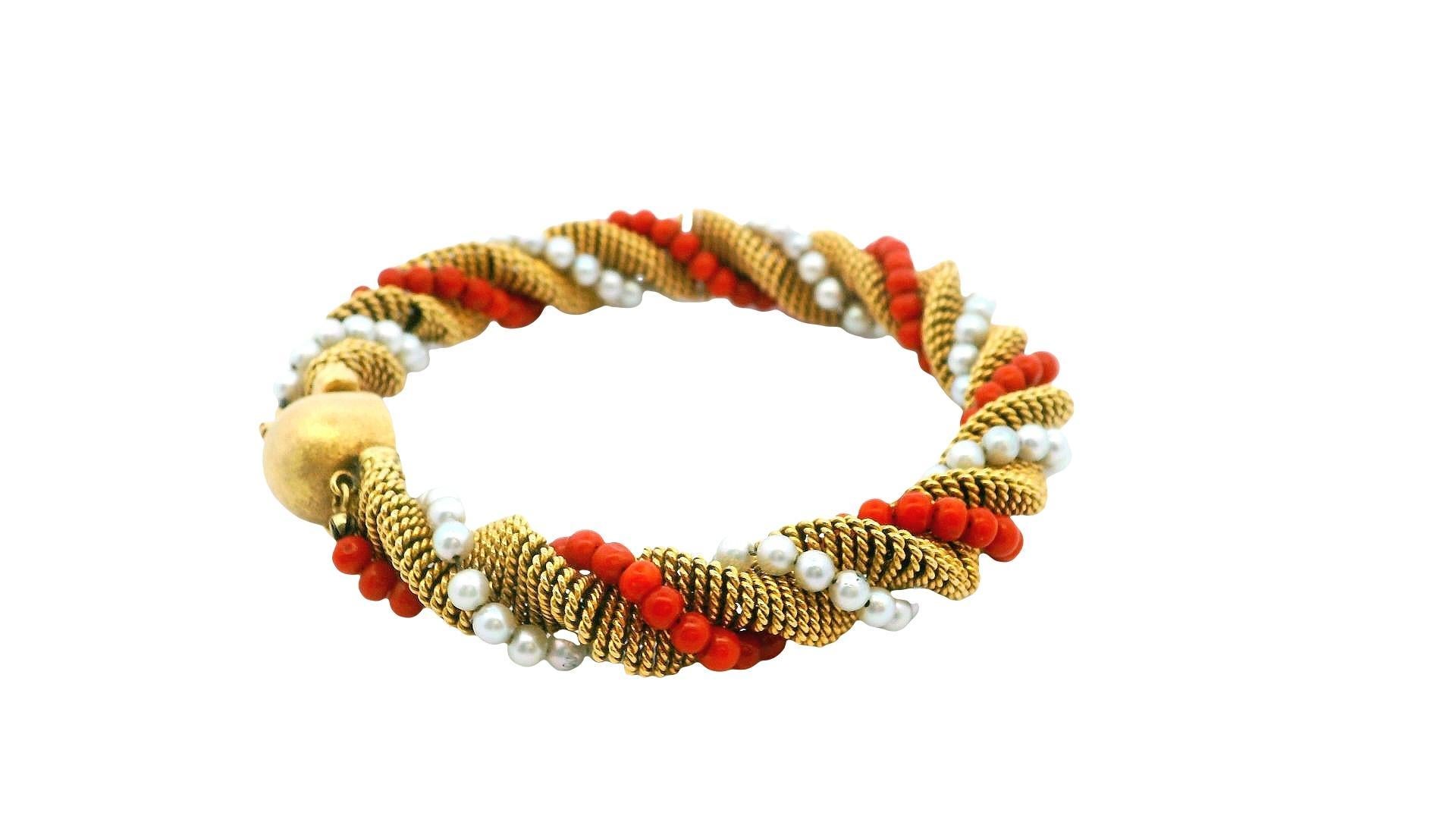 Questo splendido bracciale è un pezzo di gioielleria notevole, sapientemente realizzato in oro giallo 18 carati. Il suo sorprendente design a torsione è elegante e accattivante, con una combinazione di perle di corallo rosso vibrante e perle bianche