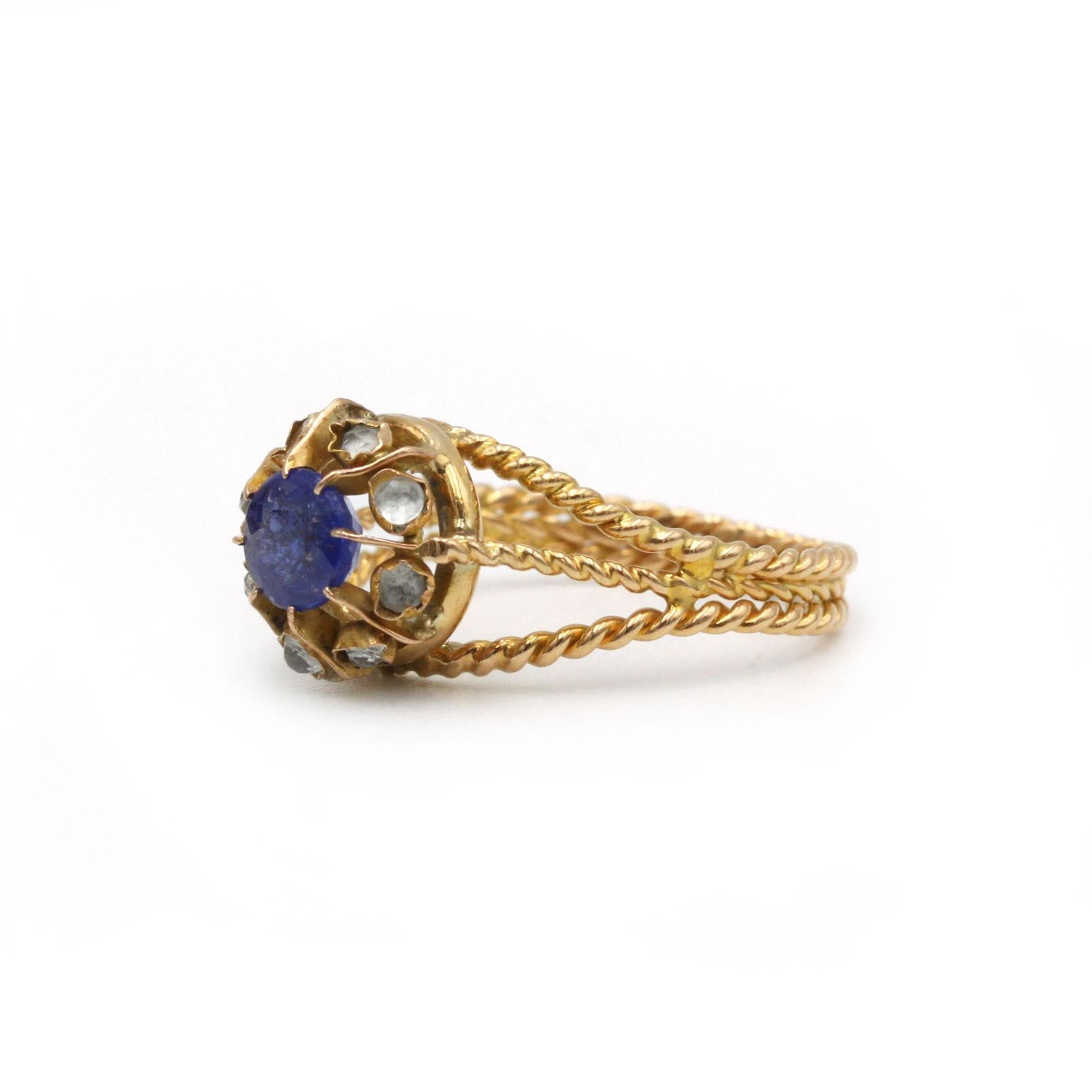 Cette élégante bague présente trois brins d'or jaune 18K (750‰) délicatement torsadés qui s'enroulent gracieusement autour du doigt. En son cœur se trouve un saphir de taille ronde d'un bleu profond, dont la riche teinte capture et reflète