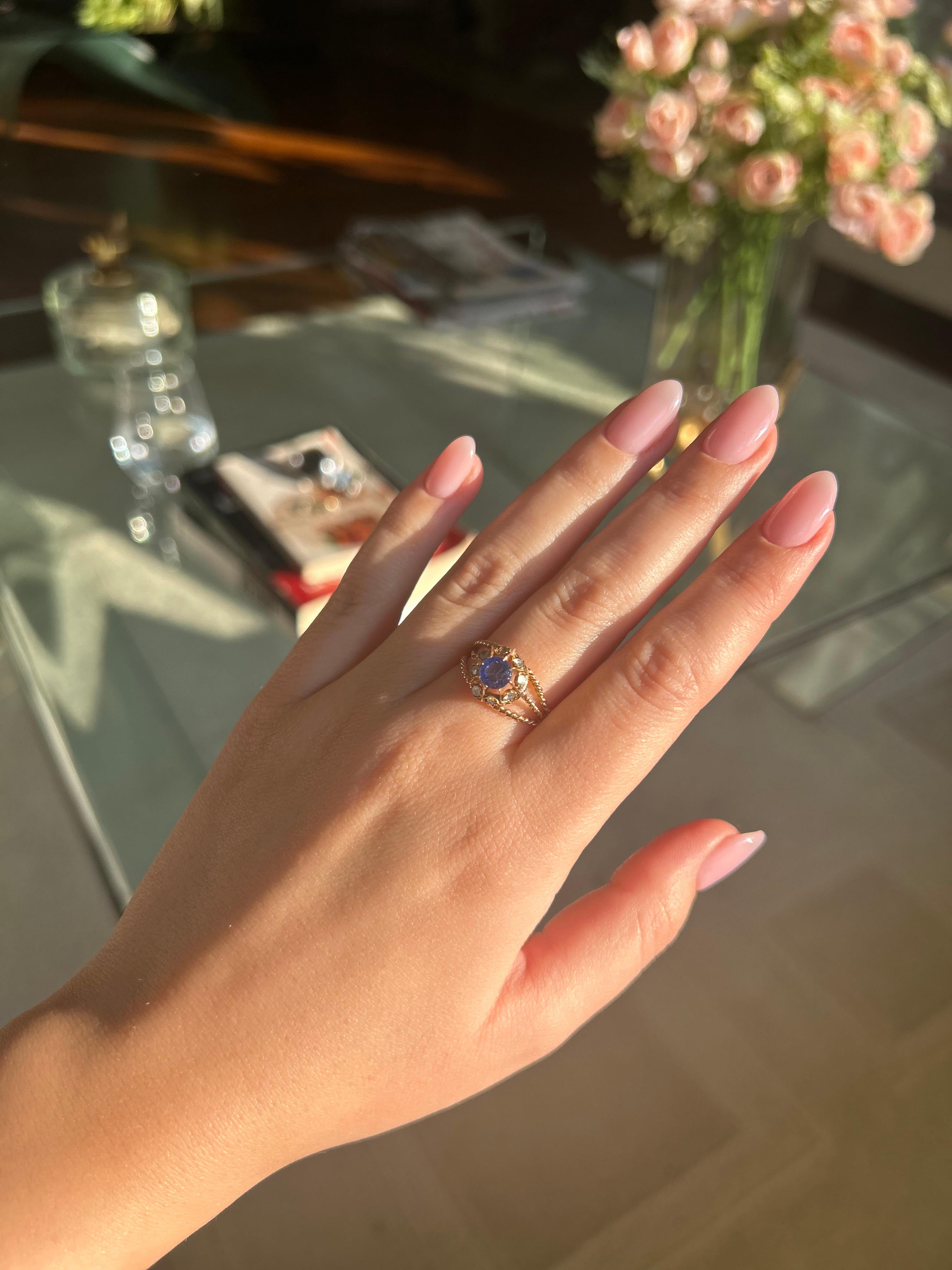 Cette élégante bague présente trois brins d'or jaune 18K (750‰) délicatement torsadés qui s'enroulent gracieusement autour du doigt. En son cœur se trouve un saphir de taille ronde d'un bleu profond, dont la riche teinte capture et reflète