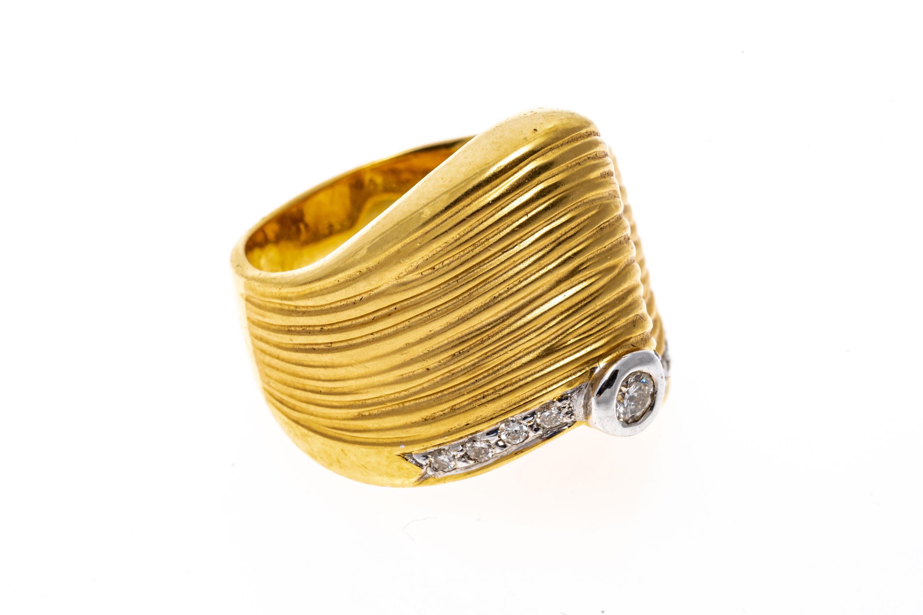 18k yellow gold ring. This yellow gold, free-form, contemporary wave ring has an ultra-wide, matte-finished and grooved body, offset on one end with a high polished edge, set with round faceted diamonds, approximately 0.10 TCW, and finished with a