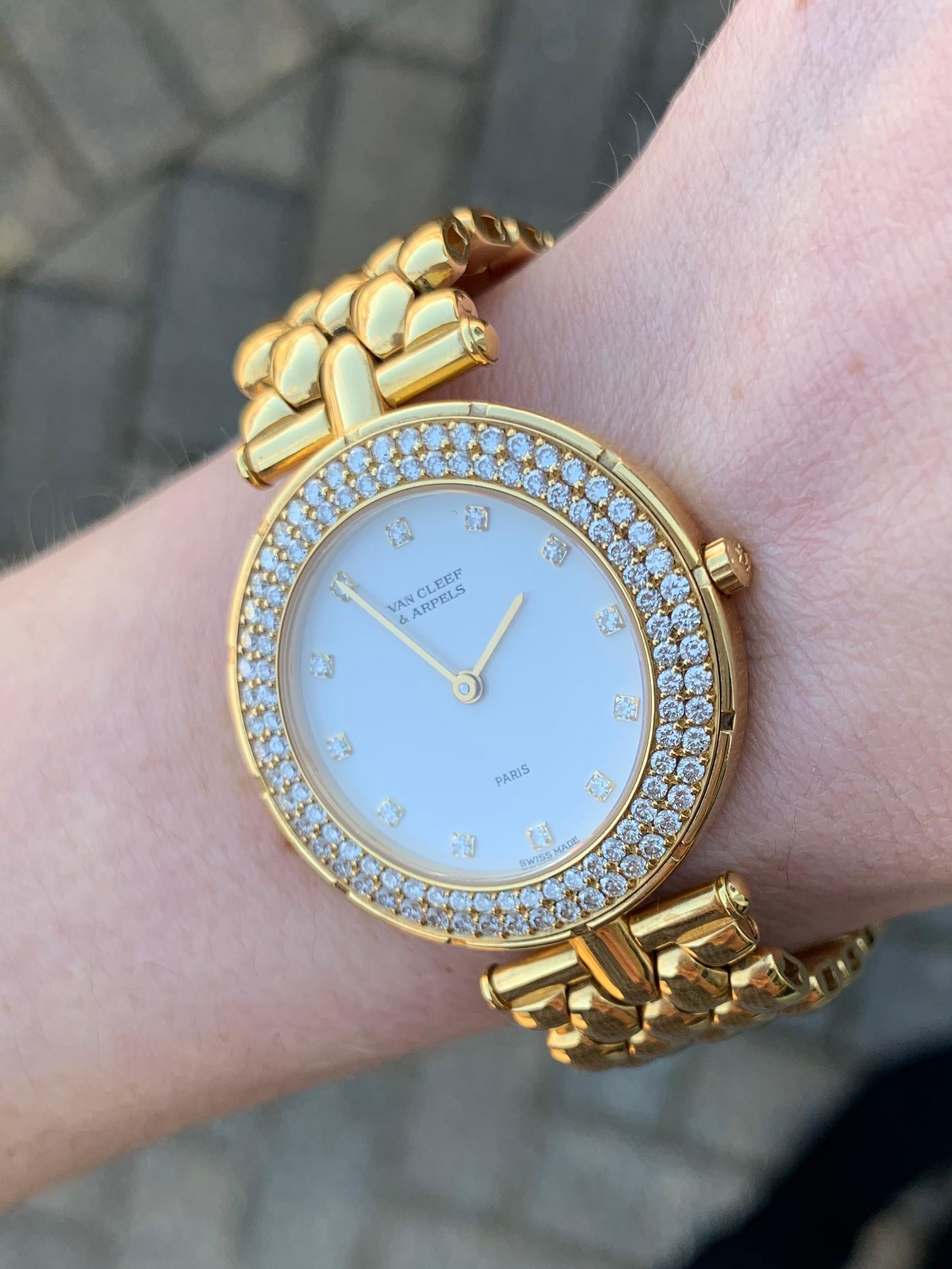A sophisticated polished 18k yellow gold Van Cleef and Arpels round diamond 'Classique' watch featuring two rows of perfectly pave set diamonds and an ivory dial with diamond hour marks. Approximate diamond total weight is 1.45 carats. Case measures