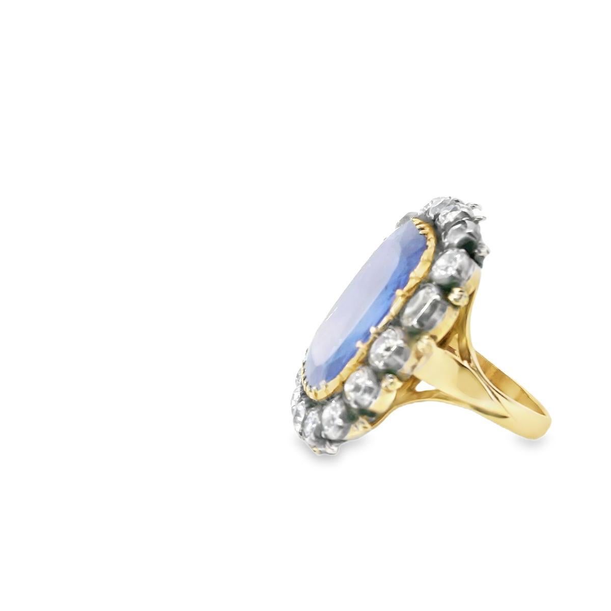 This striking antique ring is a masterpiece of timeless elegance and exceptional craftsmanship. At its center is a captivating 12.43-carat antique cushion-cut blue sapphire, radiating a deep and alluring hue. Surrounding the sapphire is a halo of