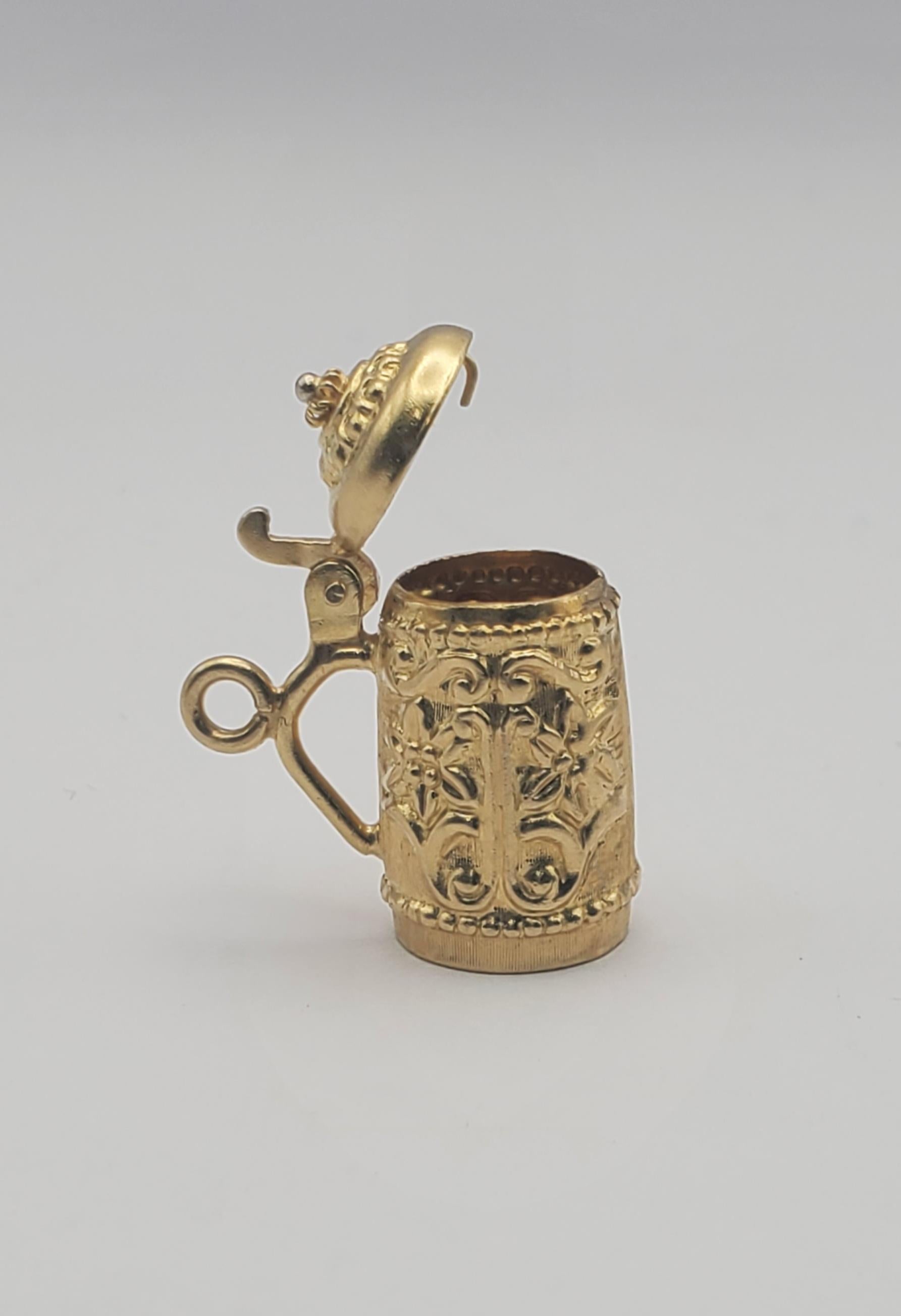 Elaborately detailed vintage 18k yellow gold lidded beer stein charm. The charm has a tensioned lid to be worn open or held closed. The body of the stein features a beautiful carved floral pattern of Edelweiss blooms. 