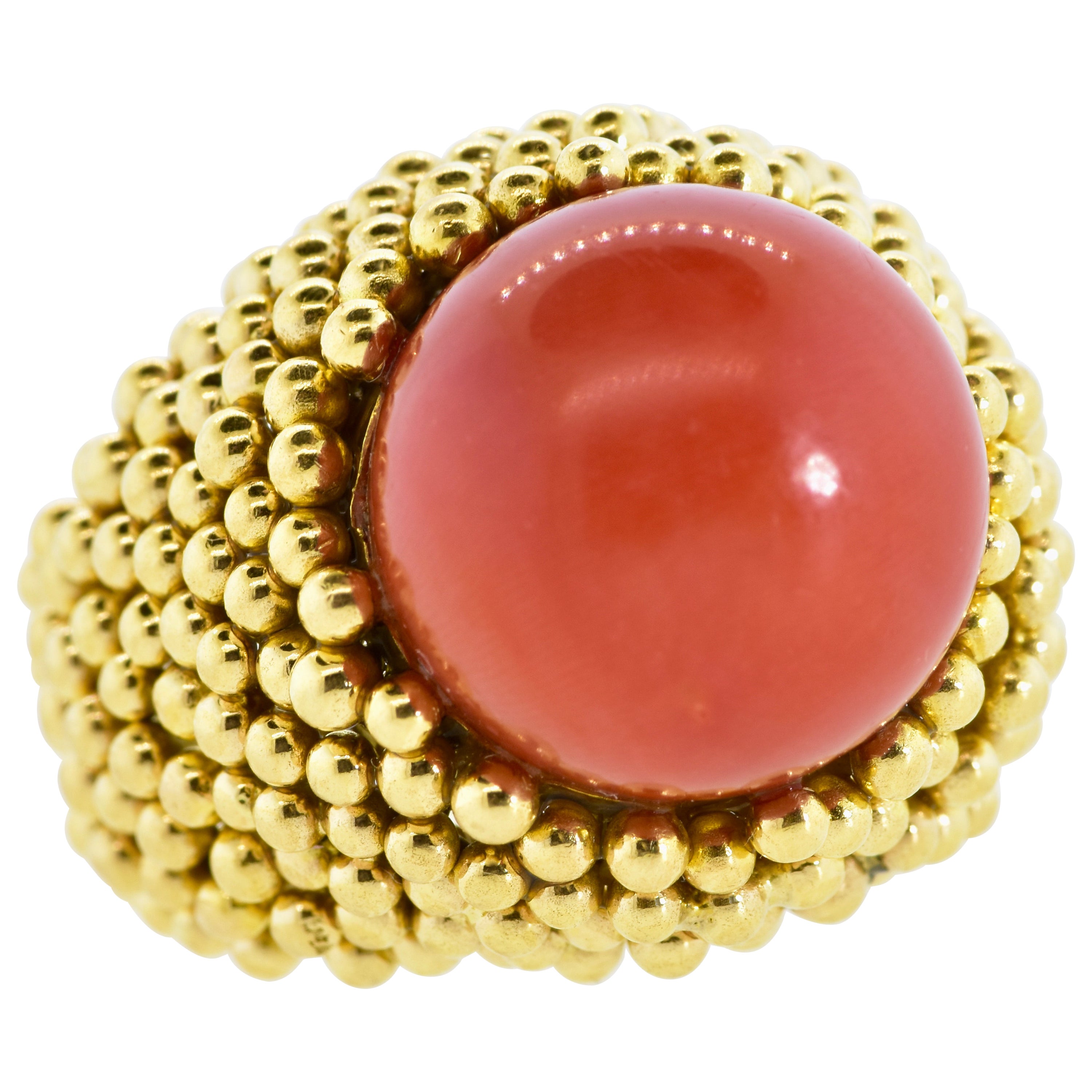 18K 1960's ring centering a deep red/orange (oxblood) natural coral bead measuring 15.5 in diameter. The coral is natural and even in color.  Underneath the stone, there is a slight color change This hand made ring is studded with yellow gold balls