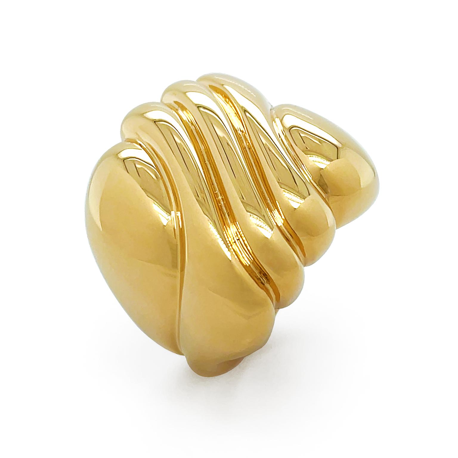 The luminous radiance of polished 18k yellow gold dances across the ring. The sleek metal features a carved asymmetrical pattern of soft waves, giving a sense of motion. Measurements for the ring are 0.875 inches (width) by 0.875 inches (length) by