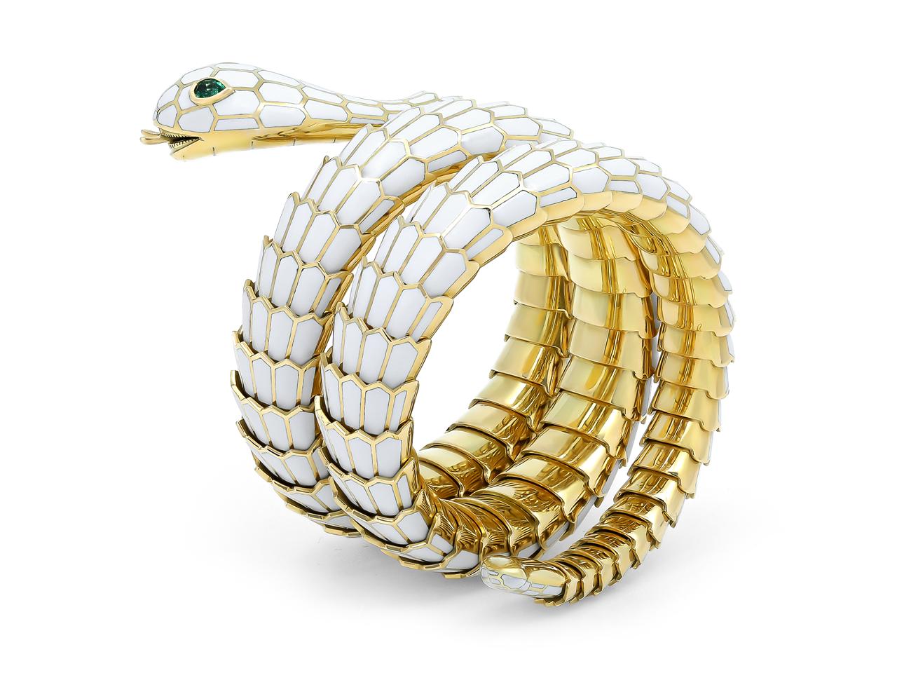 A striking 18K yellow gold wrap snake bracelet, elegantly adorned with white enamel and featuring two mesmerizing pear-cut emerald eyes.