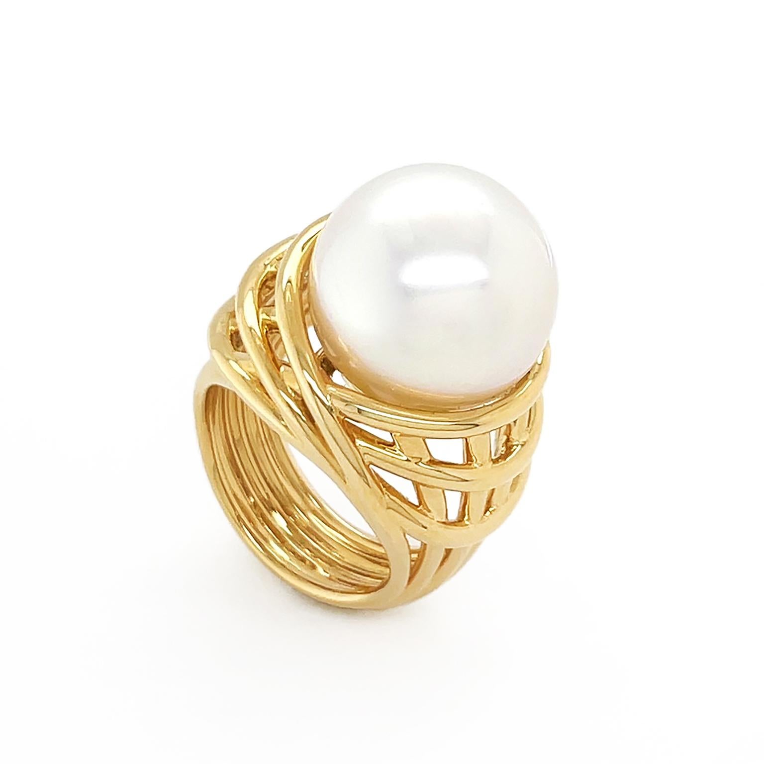 A white South Sea pearl is the apex of this ring. An 18k yellow gold shank of multiple bands intersect to fashion an openwork pattern to exalt the gem weighing 27.59 carats. The ring measures 0.94 inches (width) by 0.75 inches (length) by 1.41