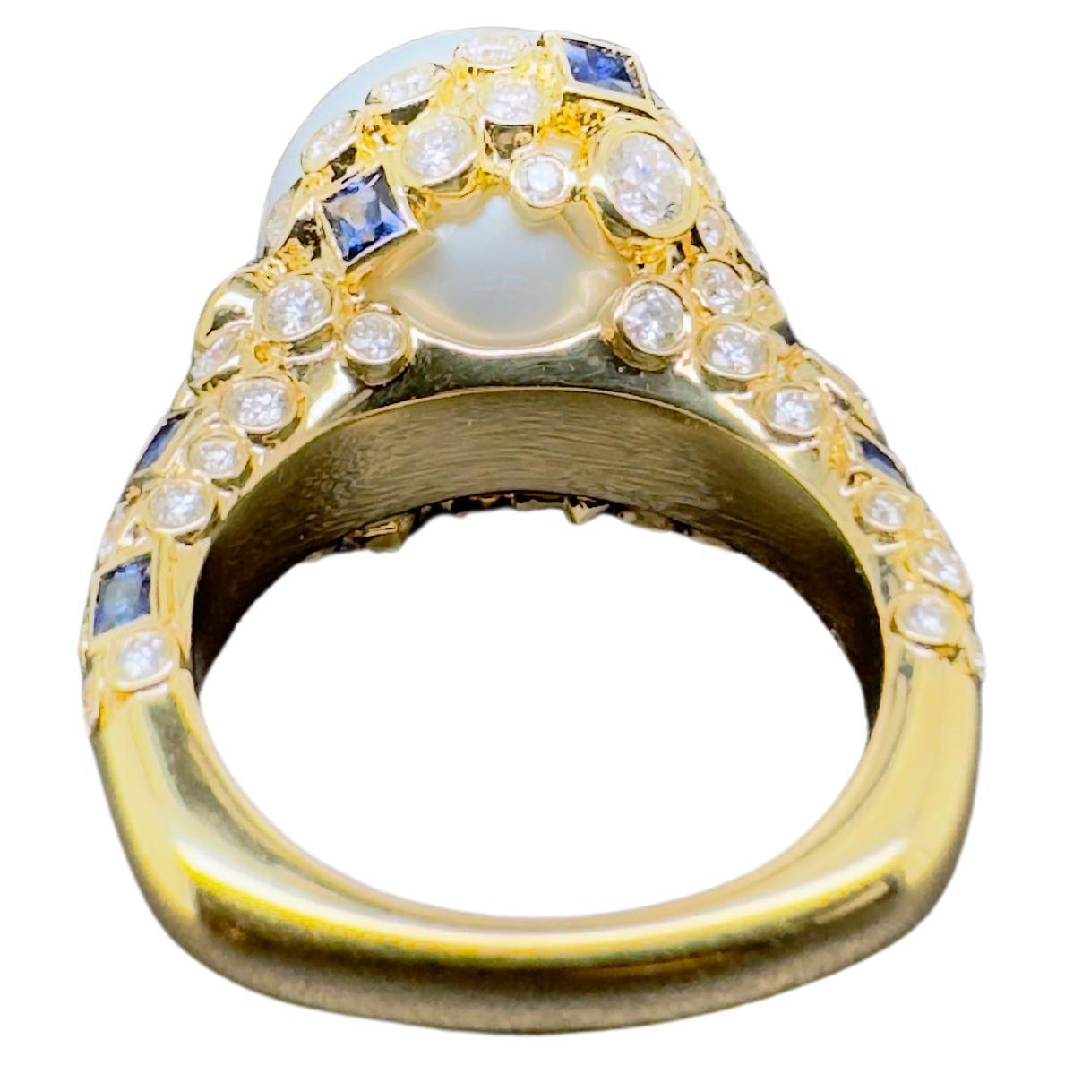 This pearl ring is an absolute masterpiece.  The 14.5 mm White South Sea Pearl is set in a custom design setting that is artistically mesmerizing.  The square blue sapphires are bezel set that scattered amongst the round brilliant diamonds bezel set