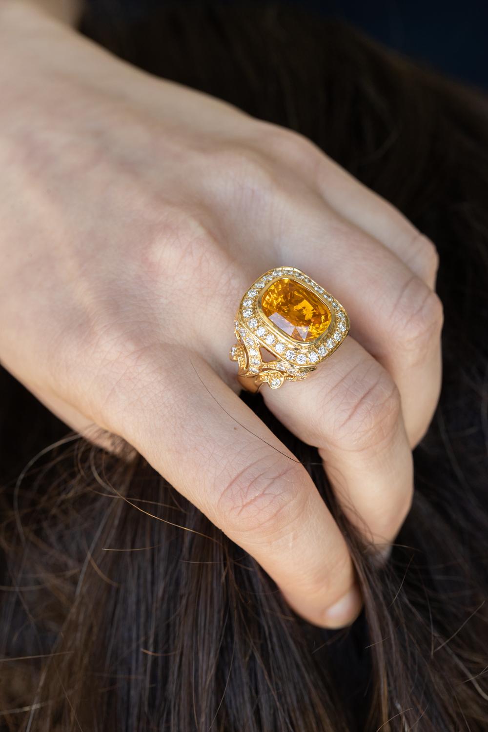 An exquisite 18K Yellow Gold Ring featuring a stunning 8.17-carat Orange Sapphire and 1.48 carats of dazzling diamonds. This luxurious piece is designed to captivate and enchant, making it the perfect statement accessory for any discerning jewelry