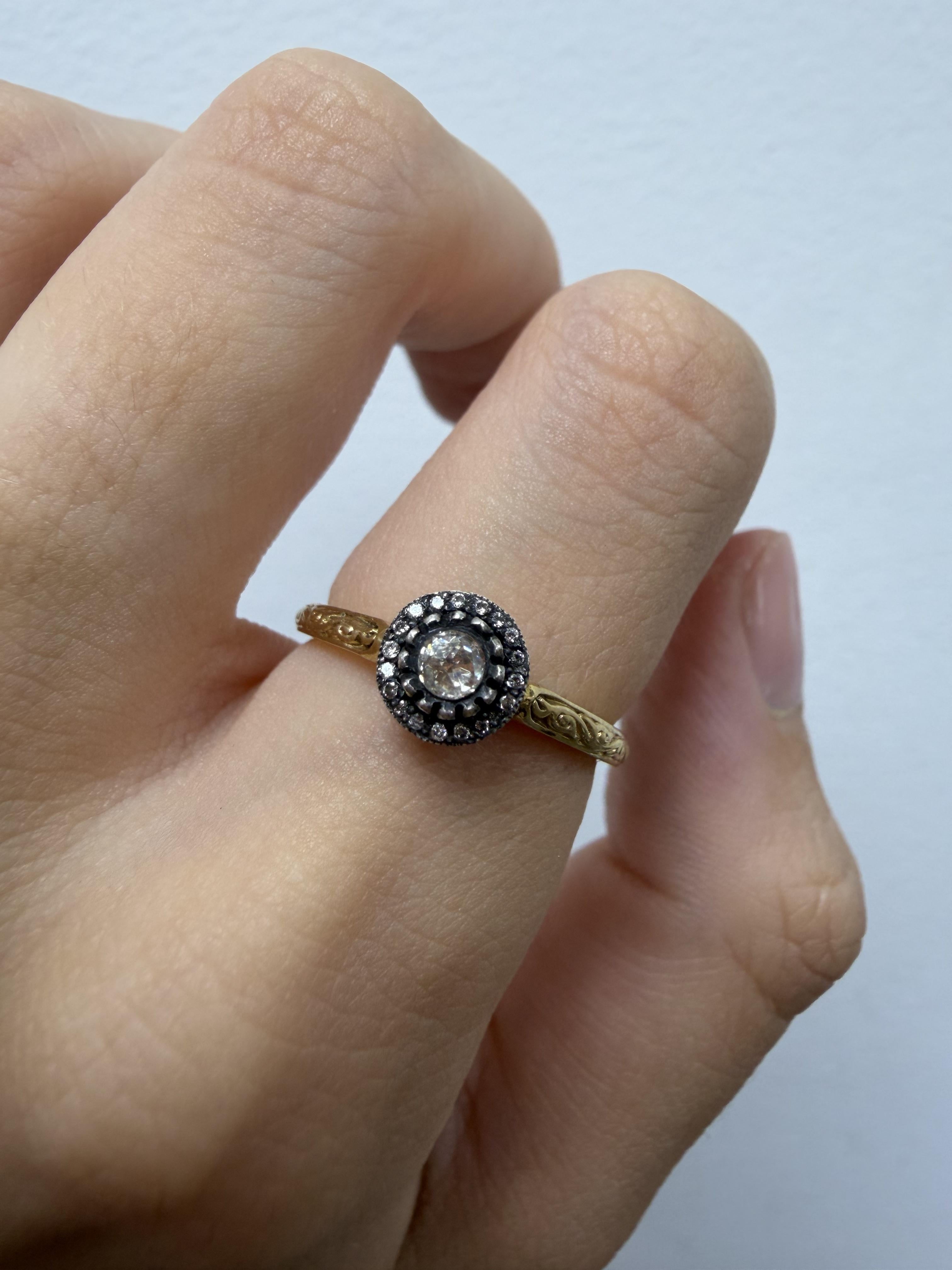 Cette élégante bague présente un halo intemporel centré de diamants taillés en rose totalisant environ 0,14 carat. Réalisé en or jaune 18 carats avec une monture en argent, il présente de délicats détails gravés à la main le long de la bande, ce qui