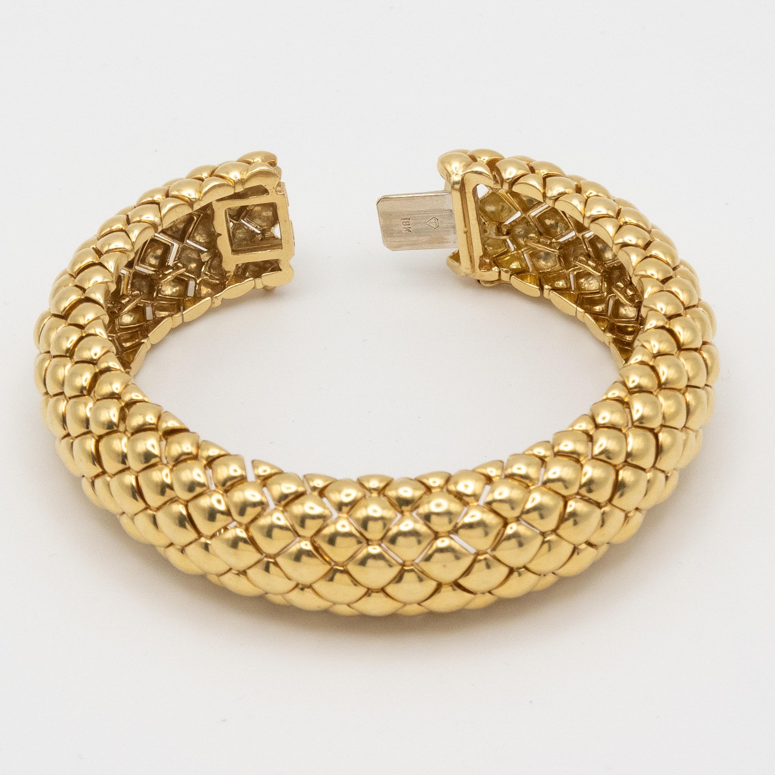 Este espectacular brazalete bombe vintage de oro amarillo de 18 quilates presenta un exquisito dibujo de 