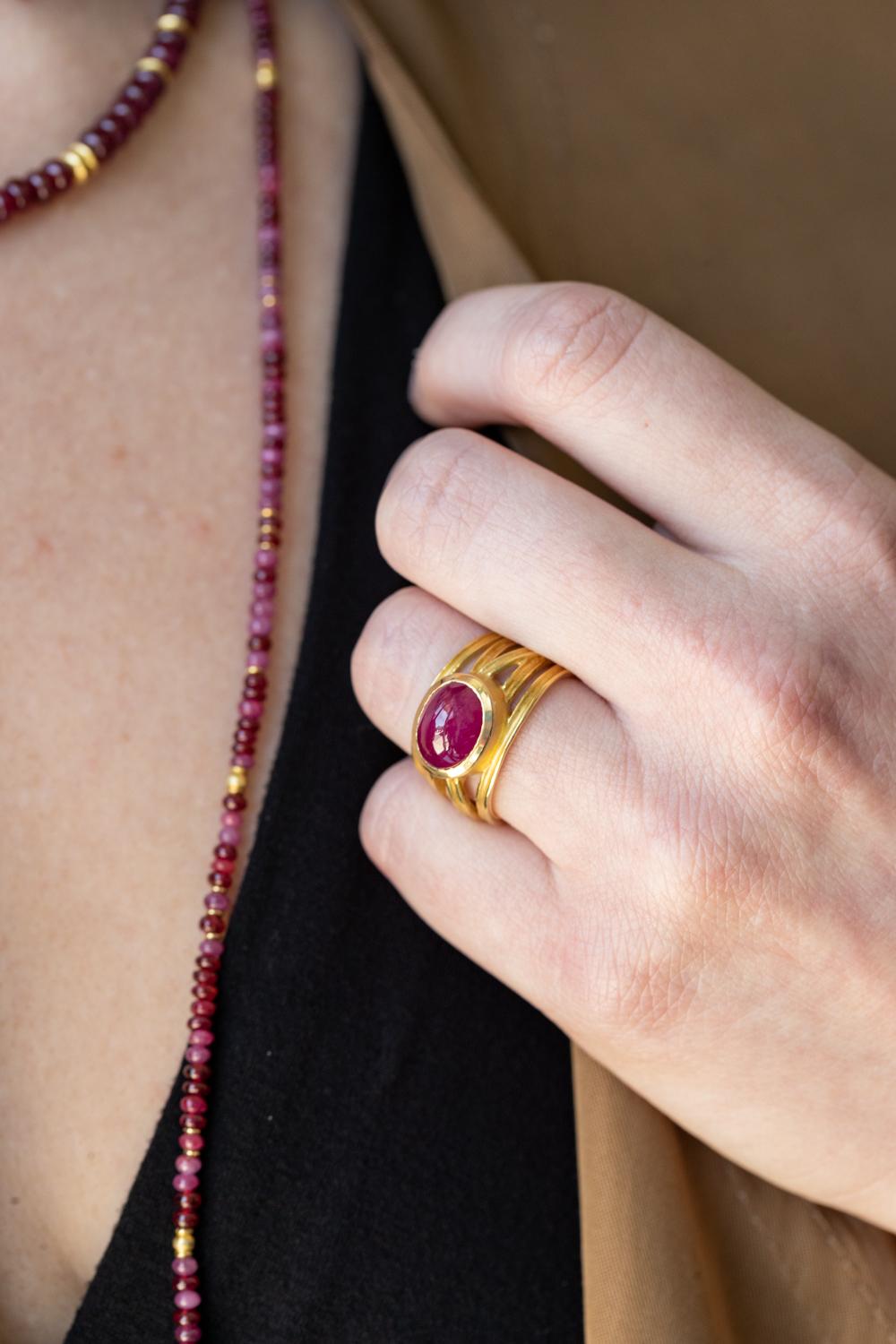 This exquisite wrapped ring with an oval cabochon ruby featuring a stunning 5.70-carat ruby center set in luxurious 18k yellow gold. This elegant ring, sized at 7.25, showcases the deep, vibrant hues of the ruby, beautifully contrasted by the warm