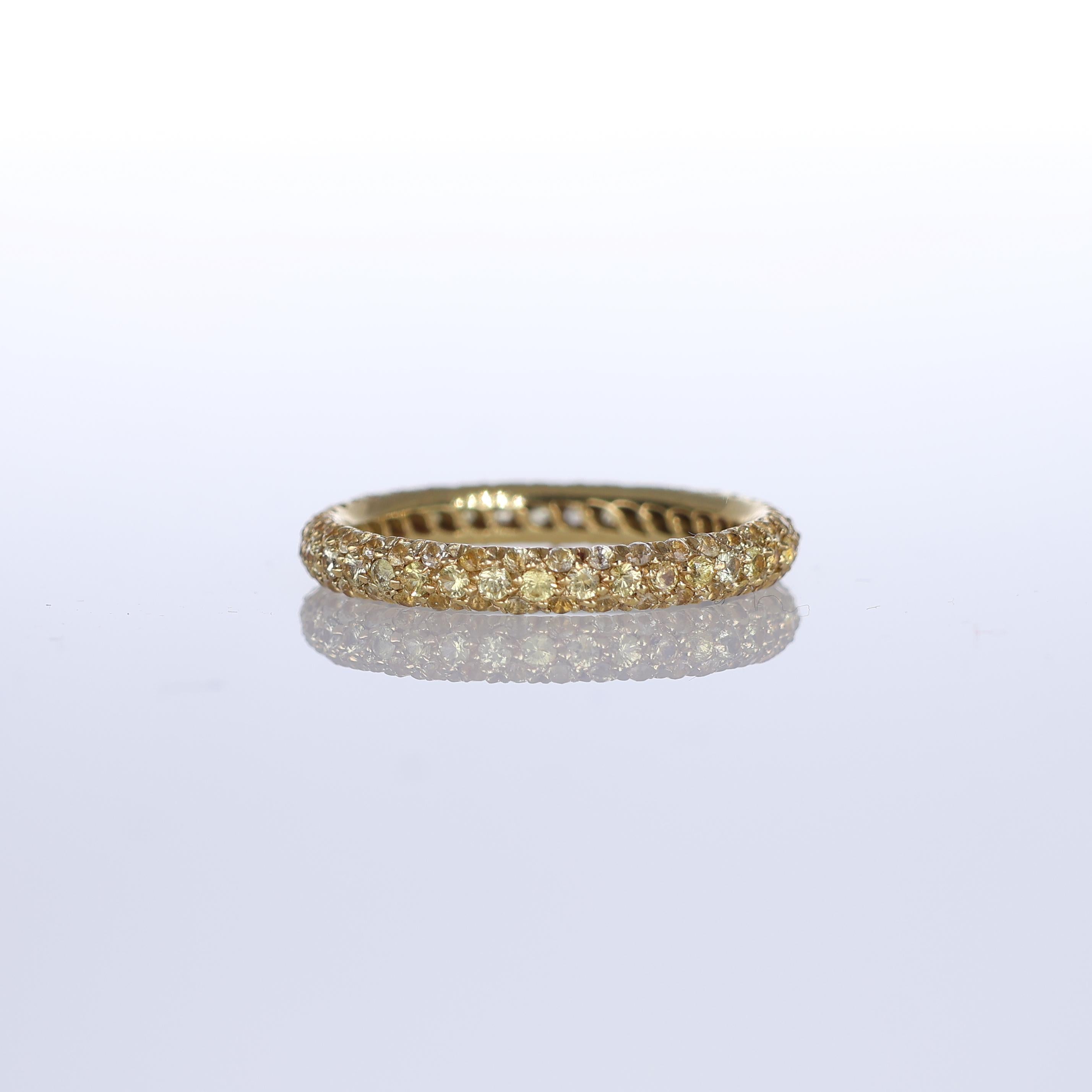An elegant band ring crafted in 18K yellow gold, adorned with a pavé of yellow sapphires totaling 1.54 carats. The warm golden tones of the metal blend harmoniously with the brilliance of the sapphires, creating a refined and luminous piece. Perfect