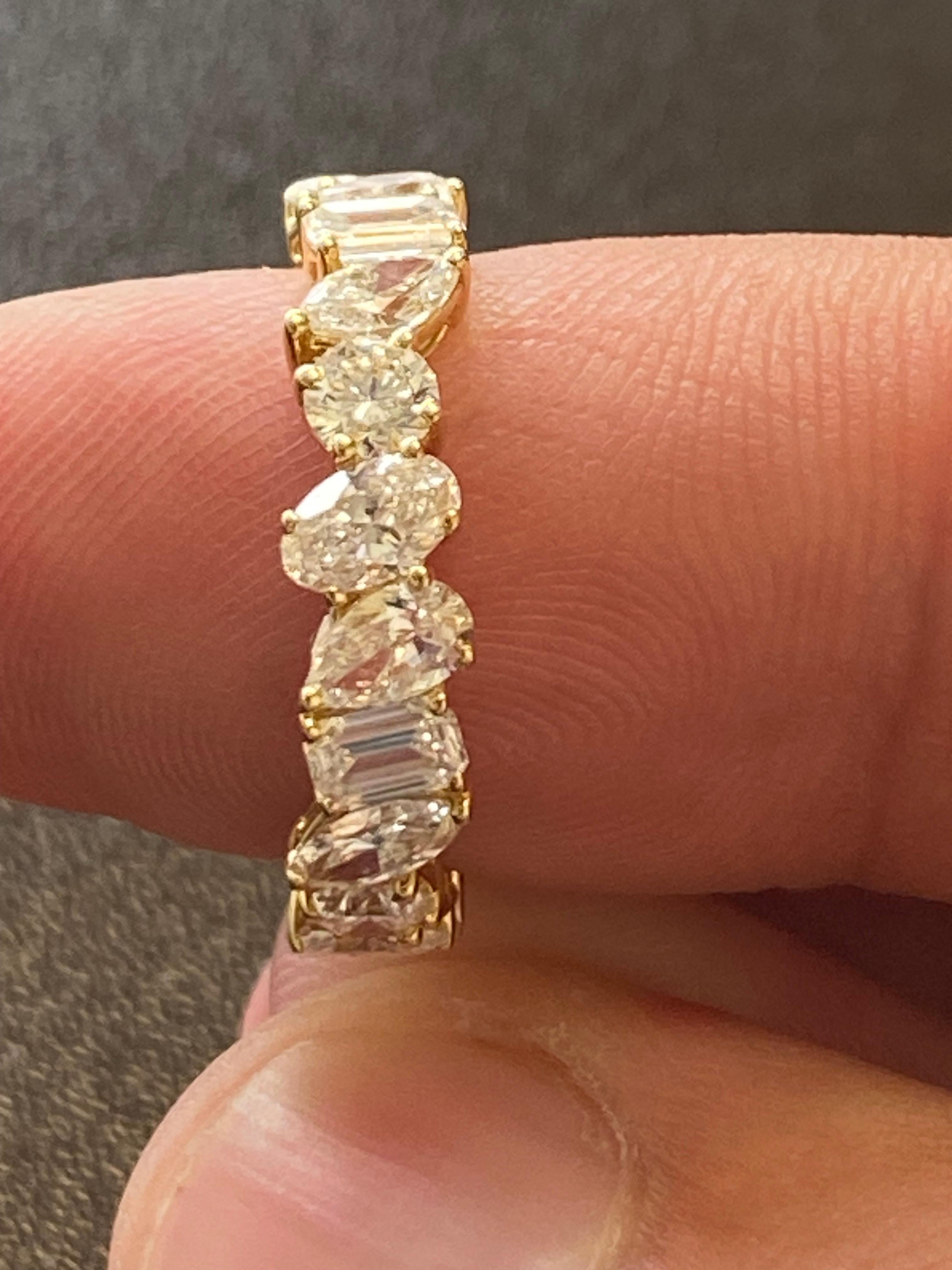 Multishape diamond eternity ring set in 18K yellow gold. The ring is set with a combination of emerald, round, pear, oval, and marquise diamonds. The total weight is 3.56 carats. The color of the stones are F and VS1 clarity. The ring is a size 6.