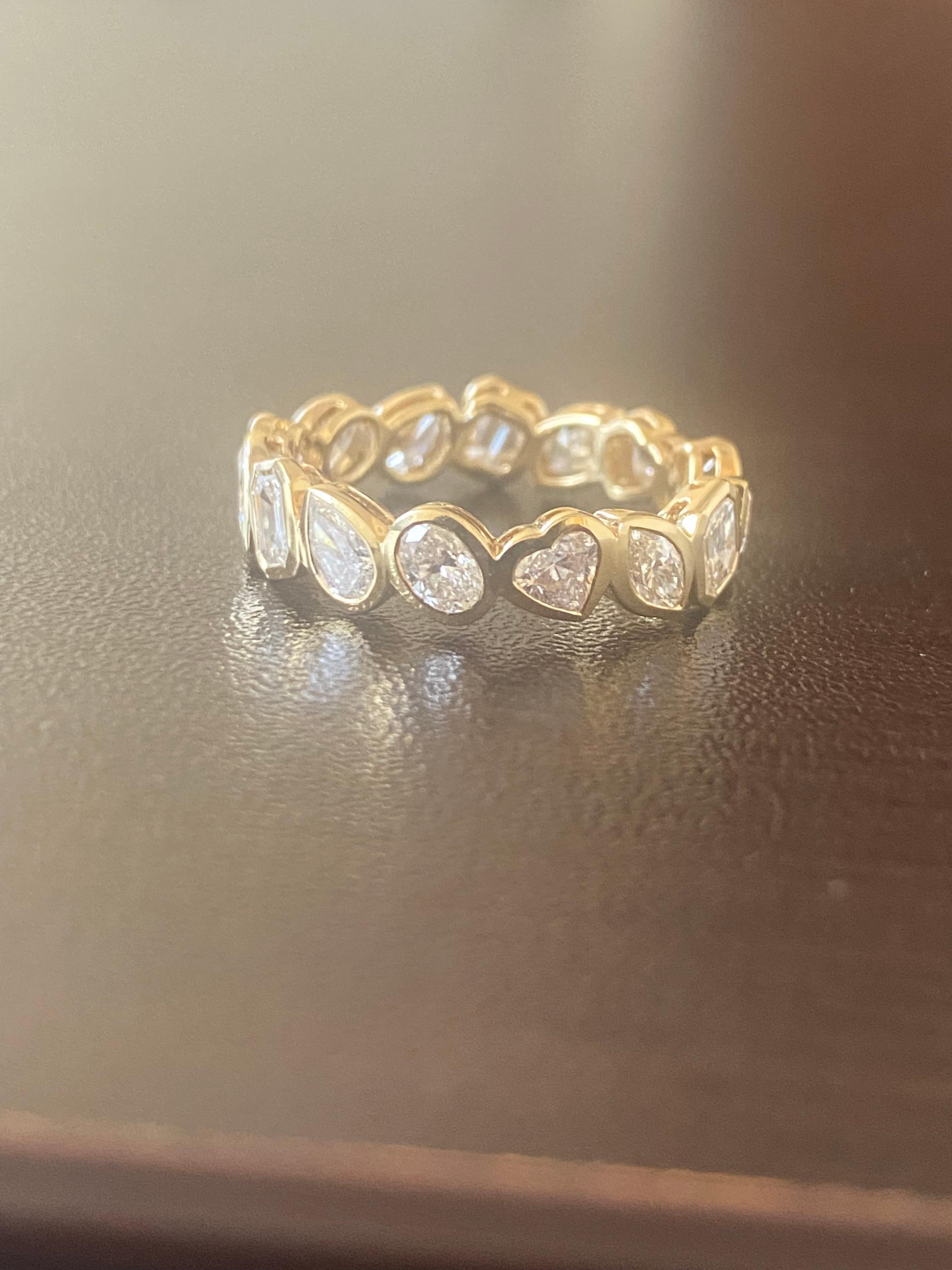 Multishape diamond ring set in a bezel set in 18K yellow gold. The ring consists of Emerald, Ovals, Princess, Marquise, and Heart shaped diamonds. The stones are F-G color and VS1-VS2 clarity. The total weight is 3.54 carats. The ring is available