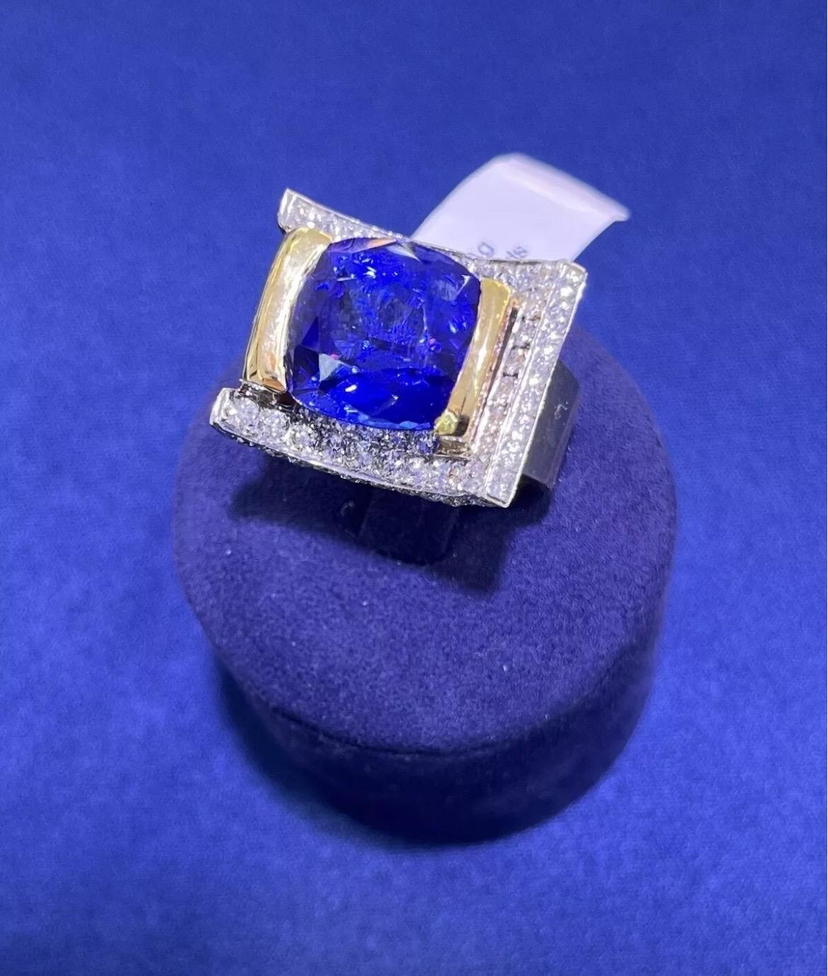 Cette spectaculaire bague de cocktail, unique en son genre, met en valeur une tanzanite de 13,44 carats de taille coussin, sertie dans une monture audacieuse et architecturale en or jaune et blanc 18 carats. La vive teinte bleu-violet de la