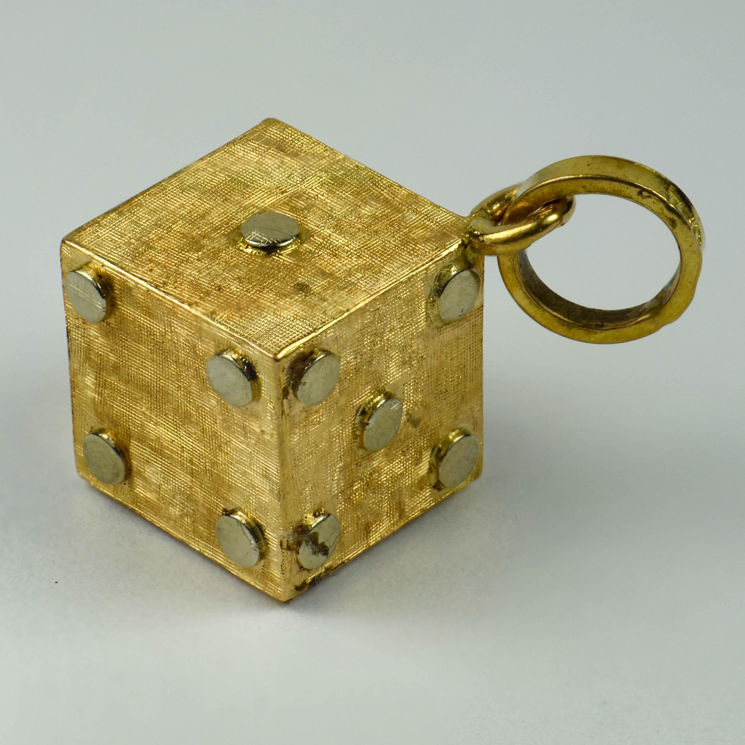 An 18 karat (18K) yellow and white gold charm pendant designed as a gambling dice cube or die with cross-hatched yellow gold faces and white gold pips. Stamped with an unknown makers mark SLA and the French import mark for 18 karat gold between