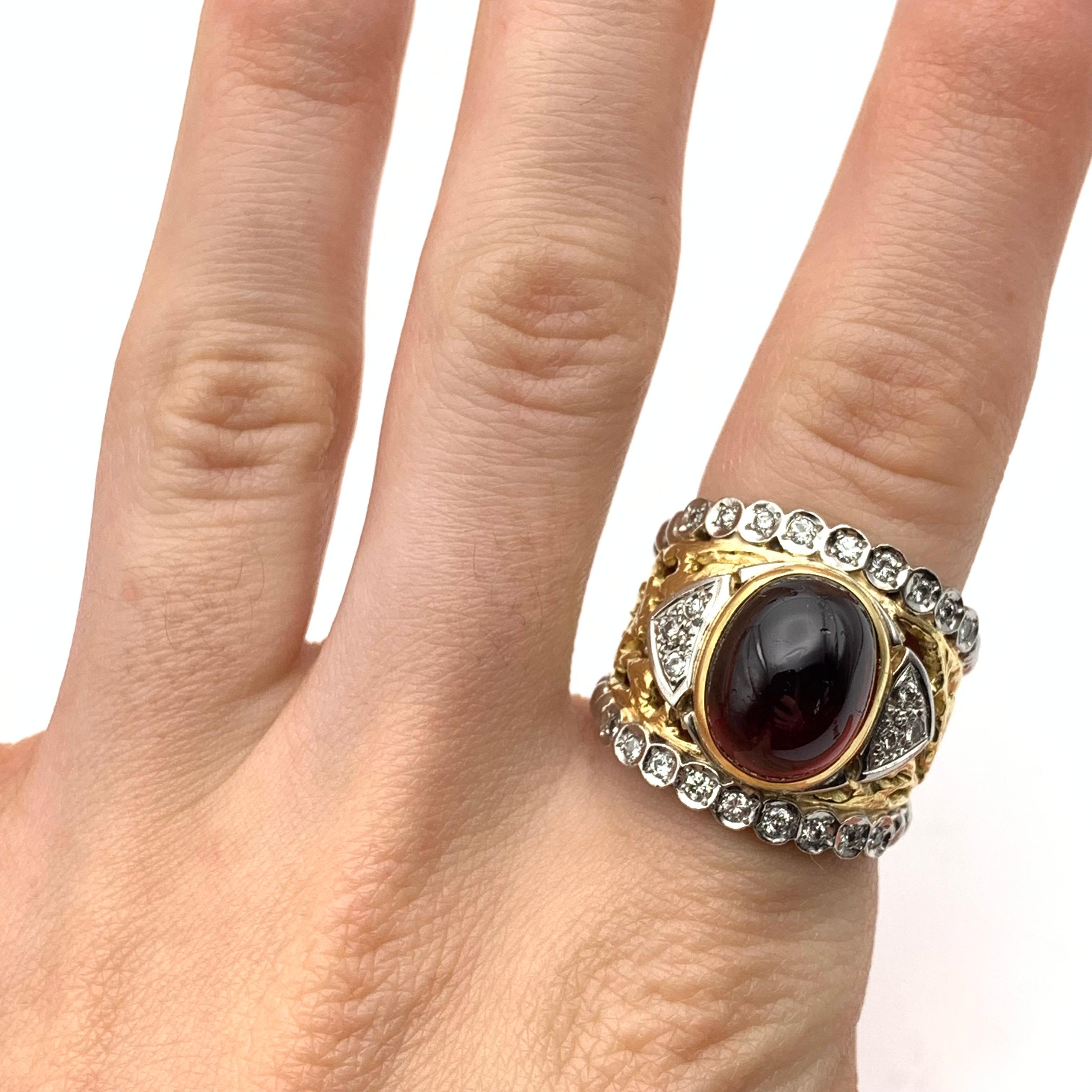 This ring is part of our estate collection and is rich with regal charm! It is set in 18-karat yellow gold with platinum rails to accent the ring. It is bezel set with one cabochon almandine garnet measuring approximately 9.60 carats. Surrounding