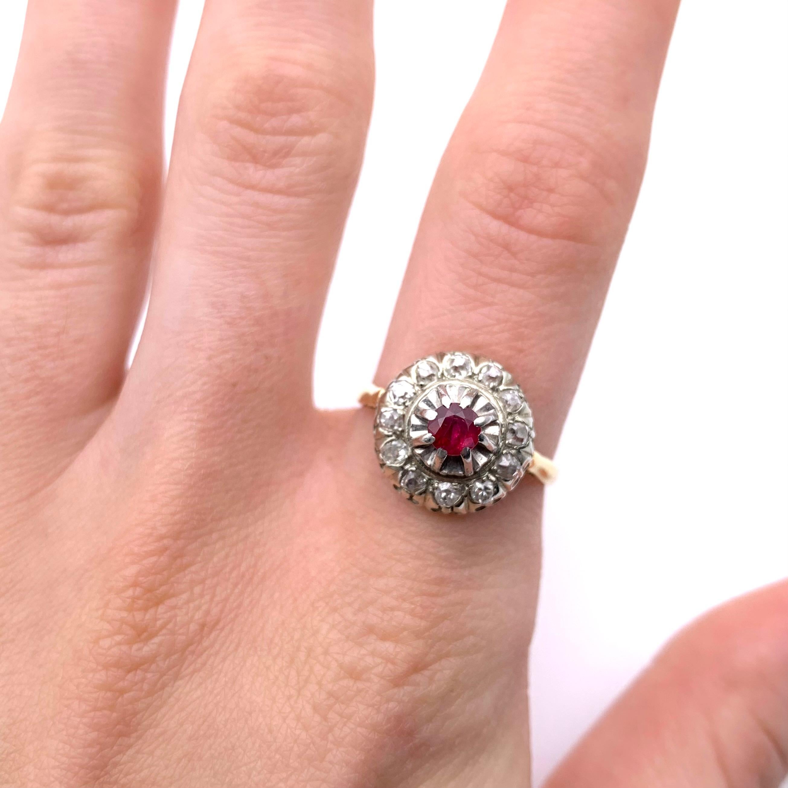 This ring is a part of our estate collection. It was purchased from a jeweler in Chartes, France. It features a yellow gold shank with a platinum head. The center stone is a round ruby measuring 0.26 carats. It is surrounded by 12 old mine-cut