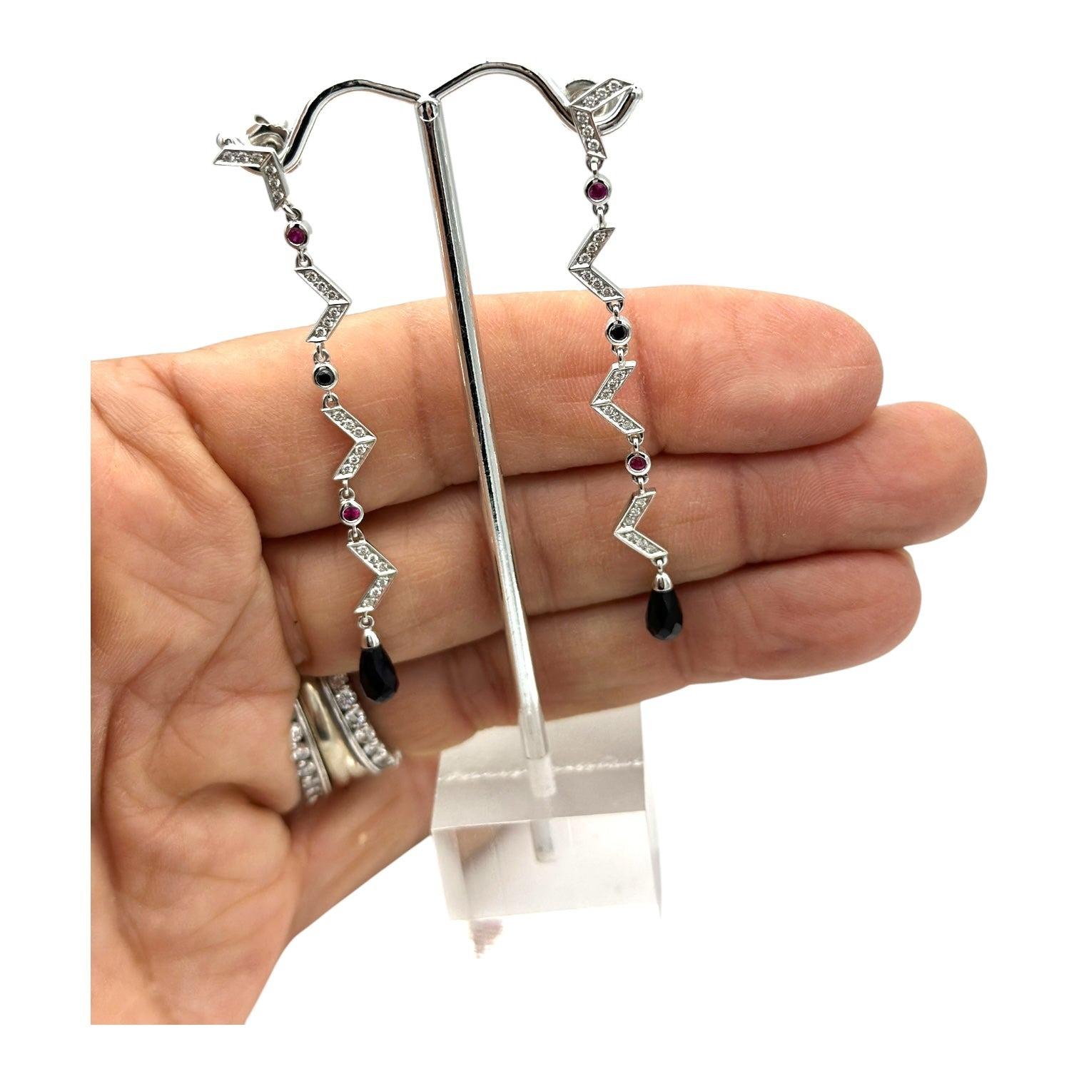 New, and crafted with 18kt gold, these Chevron-style Dangle Earrings feature sparkling diamonds, rubies, and sapphires. The elegant design adds a touch of sophistication to any outfit. Handmade by skilled artisans, these earrings are a perfect