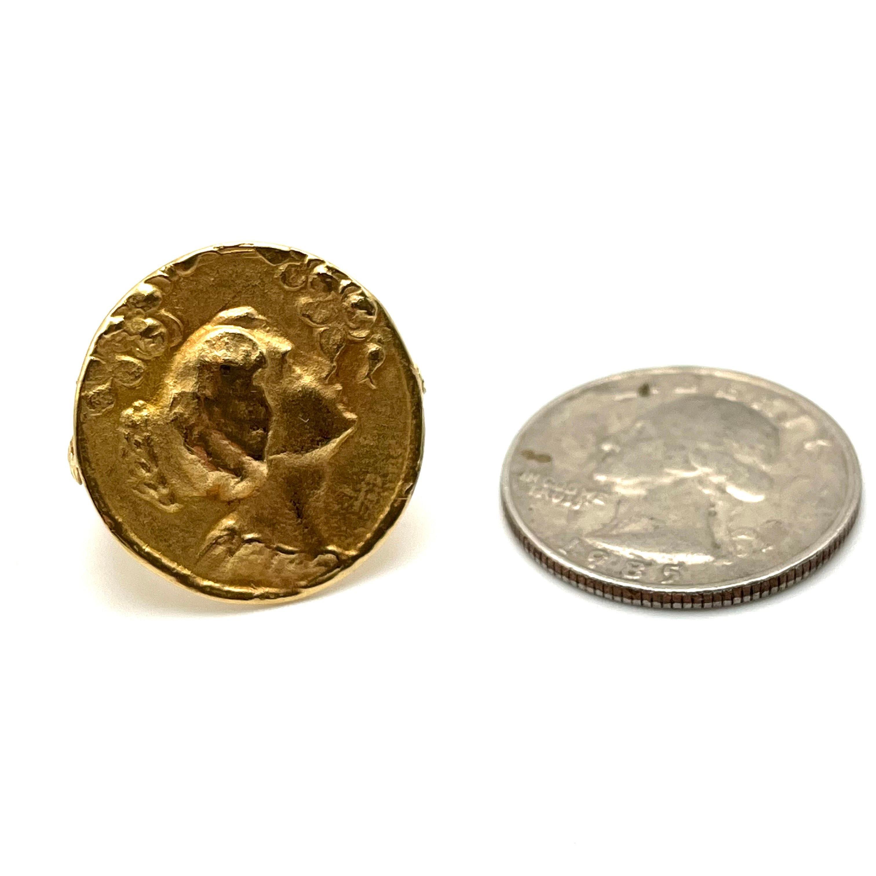 This elegant coin motif ring is set in 18-karat gold as stamped. It was originally purchased from Neiman Marcus. The frontal image is a feminine side profile with hammered detailing measuring 22.7 mm in diameter. Delicate leaves can be found on